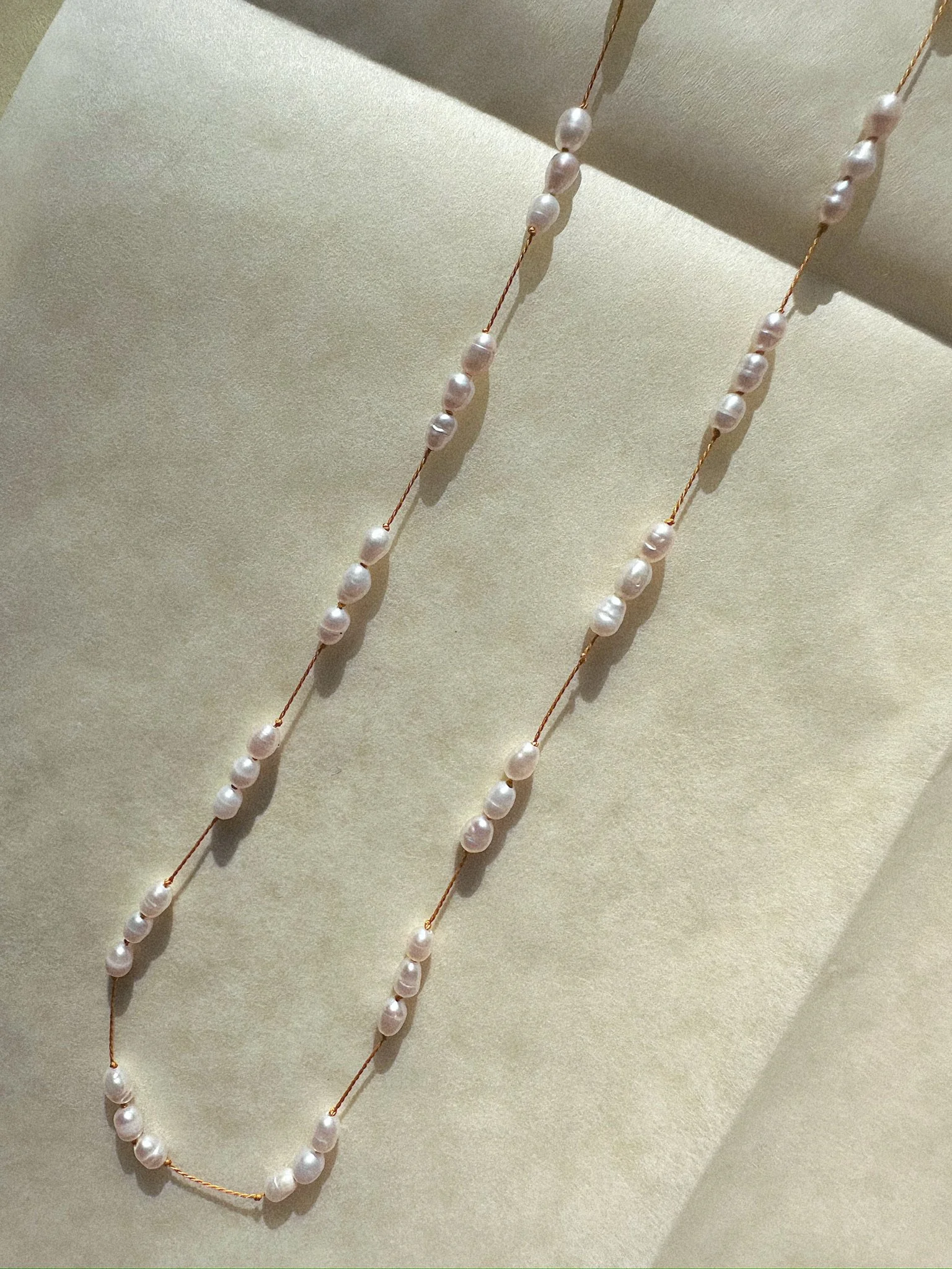 Overhead of necklace pearls on yellow silk