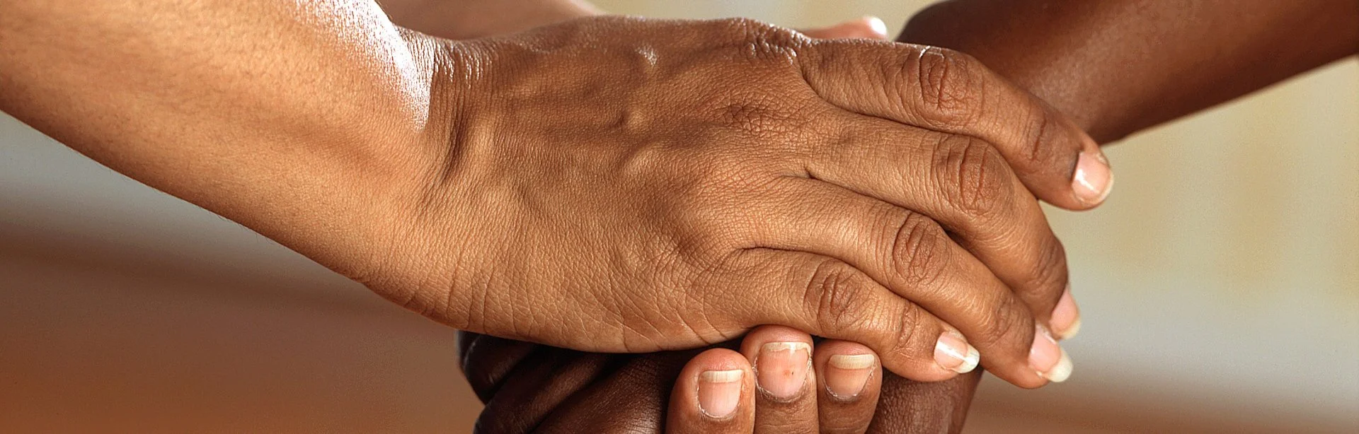 Close-up of two people's hands clasped together in support
