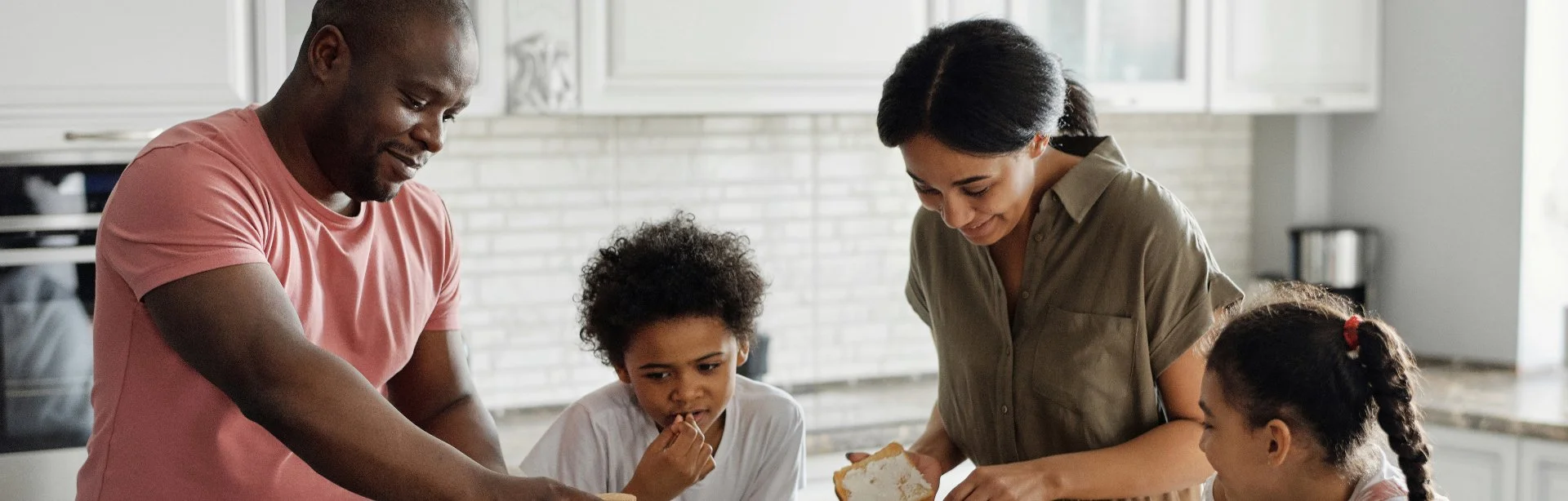 Family of four making sandwiches together in the kitchen