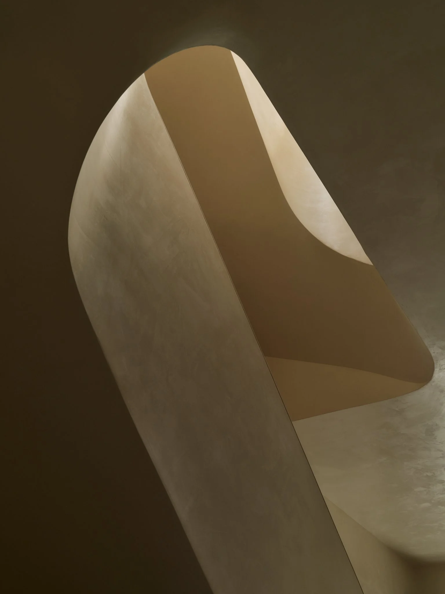 Close-up of a large, curved architectural structure with smooth, light-colored surfaces and shadowed areas, possibly part of a modern building or sculpture.