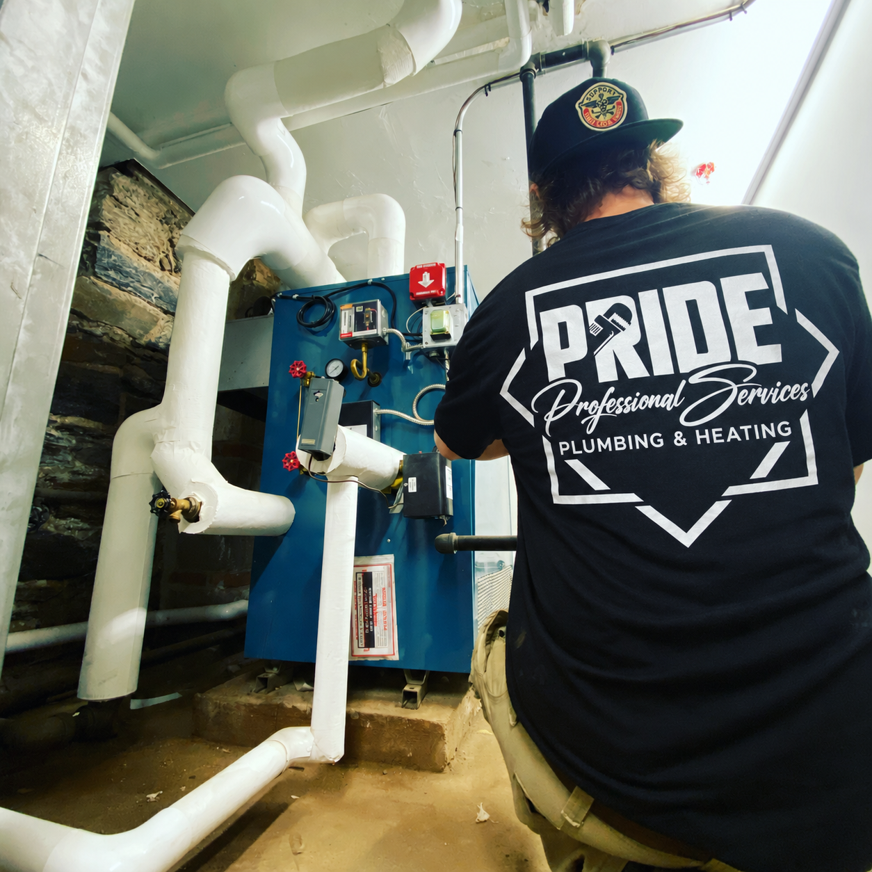 Pride Professional Services technician wearing a company-logo shirt while working beside a boiler.