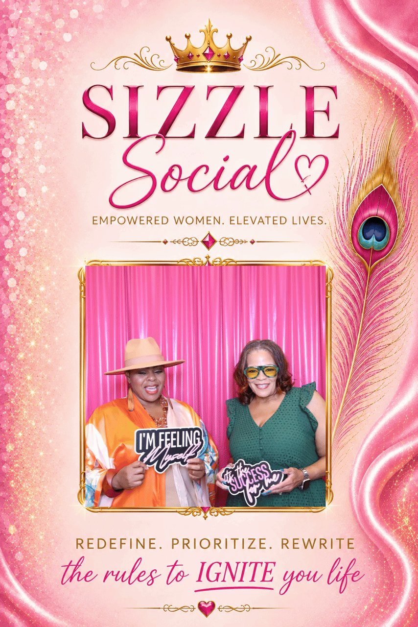 Two women smiling and holding signs at the Sizzle Social event, with pink and gold decorative background and a peacock feather.