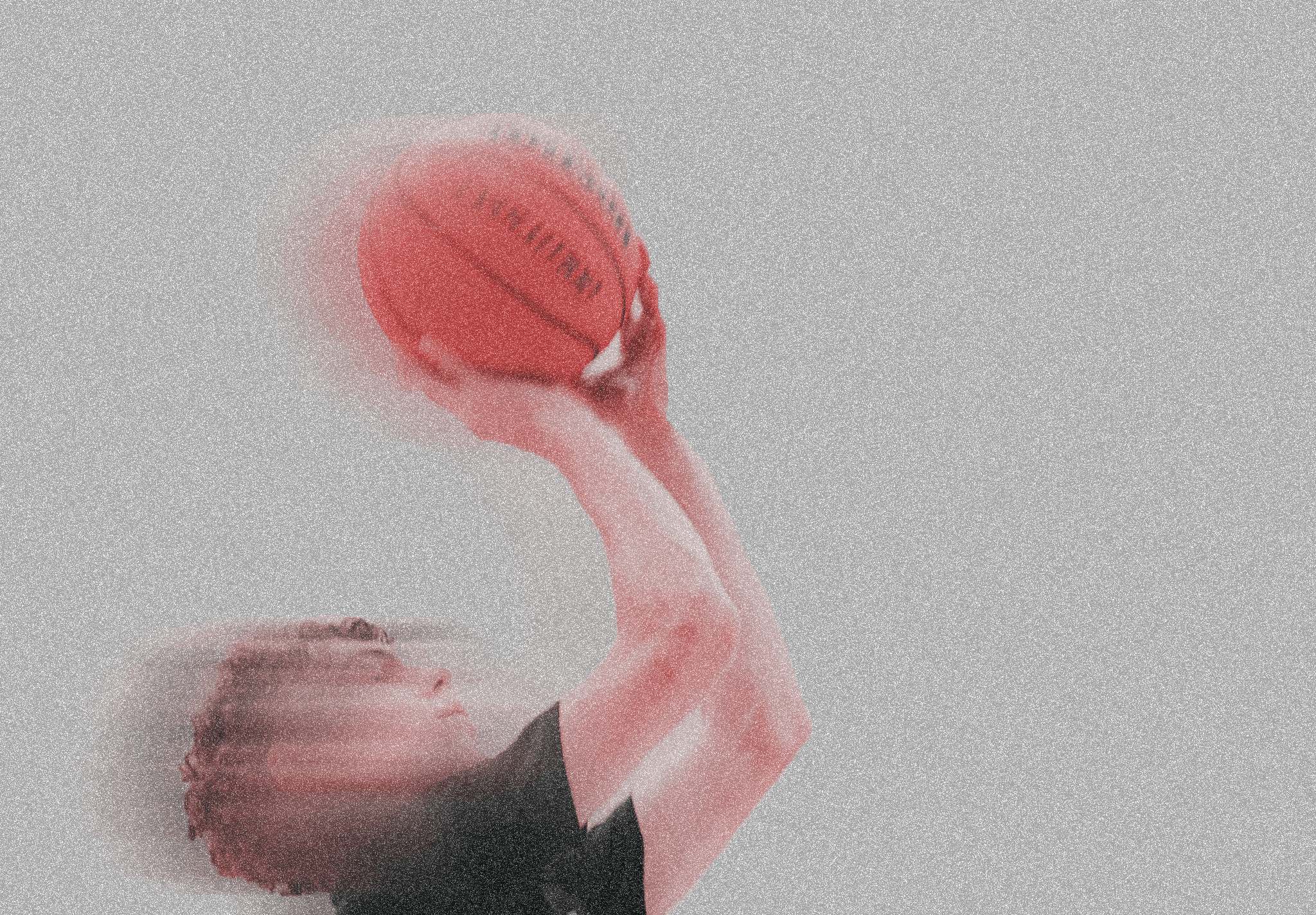 A person holding a basketball against a dark background.