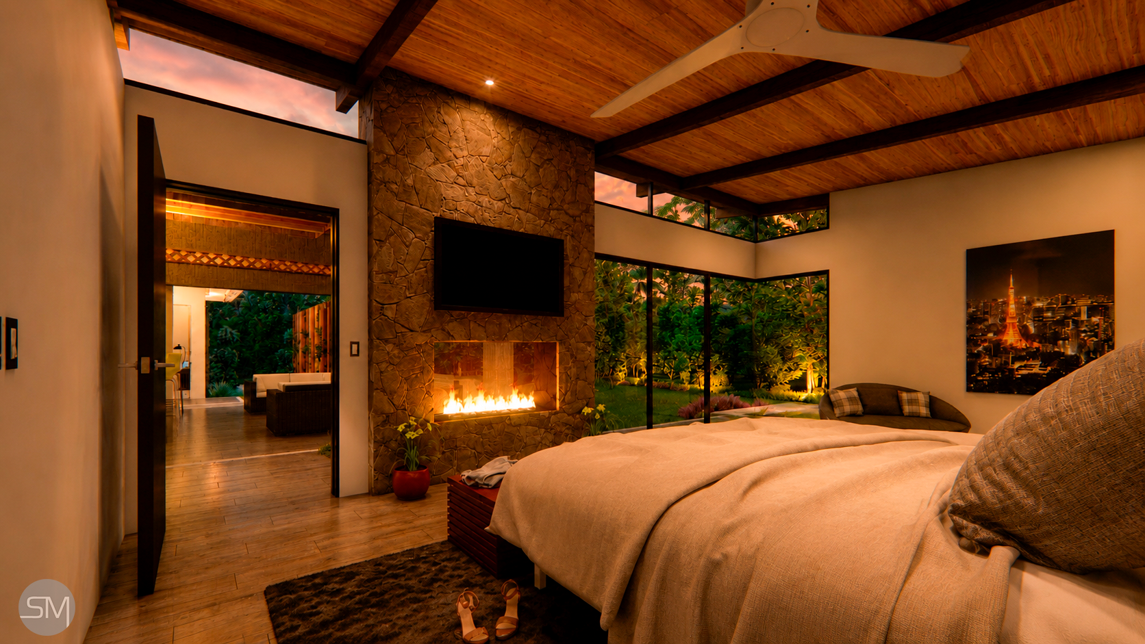 A cozy bedroom with a view of a lush garden outside. The room features a stone fireplace, a flat-screen TV, and large windows. The wooden ceiling has exposed beams and a ceiling fan. There's a bed with beige bedding, a colorful painting of a cityscap