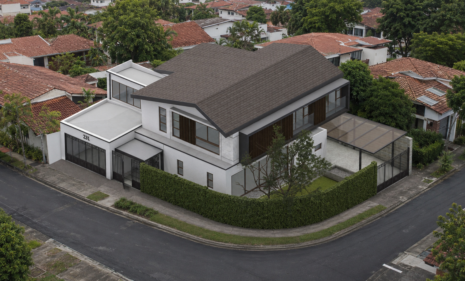A modern two-story house with a brown gabled roof, white walls, and large windows, situated on a corner lot with a green hedge surrounding it. The property includes a small yard, a paved driveway, and a glass-covered patio area, all in a residential 