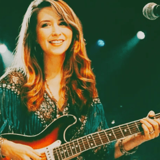 Lori Ann playing a strat guitar at a performance.