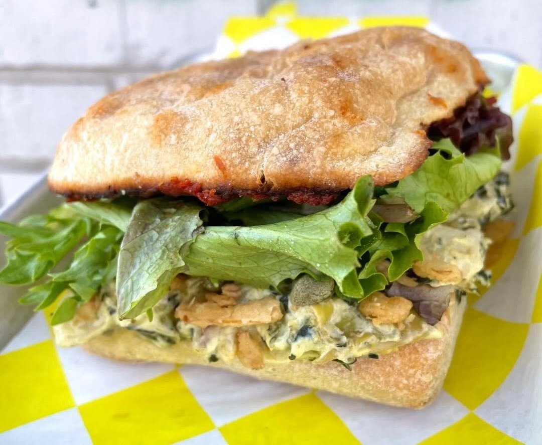 Sandwich with lettuce, chicken salad, and a toasted baguette bun.