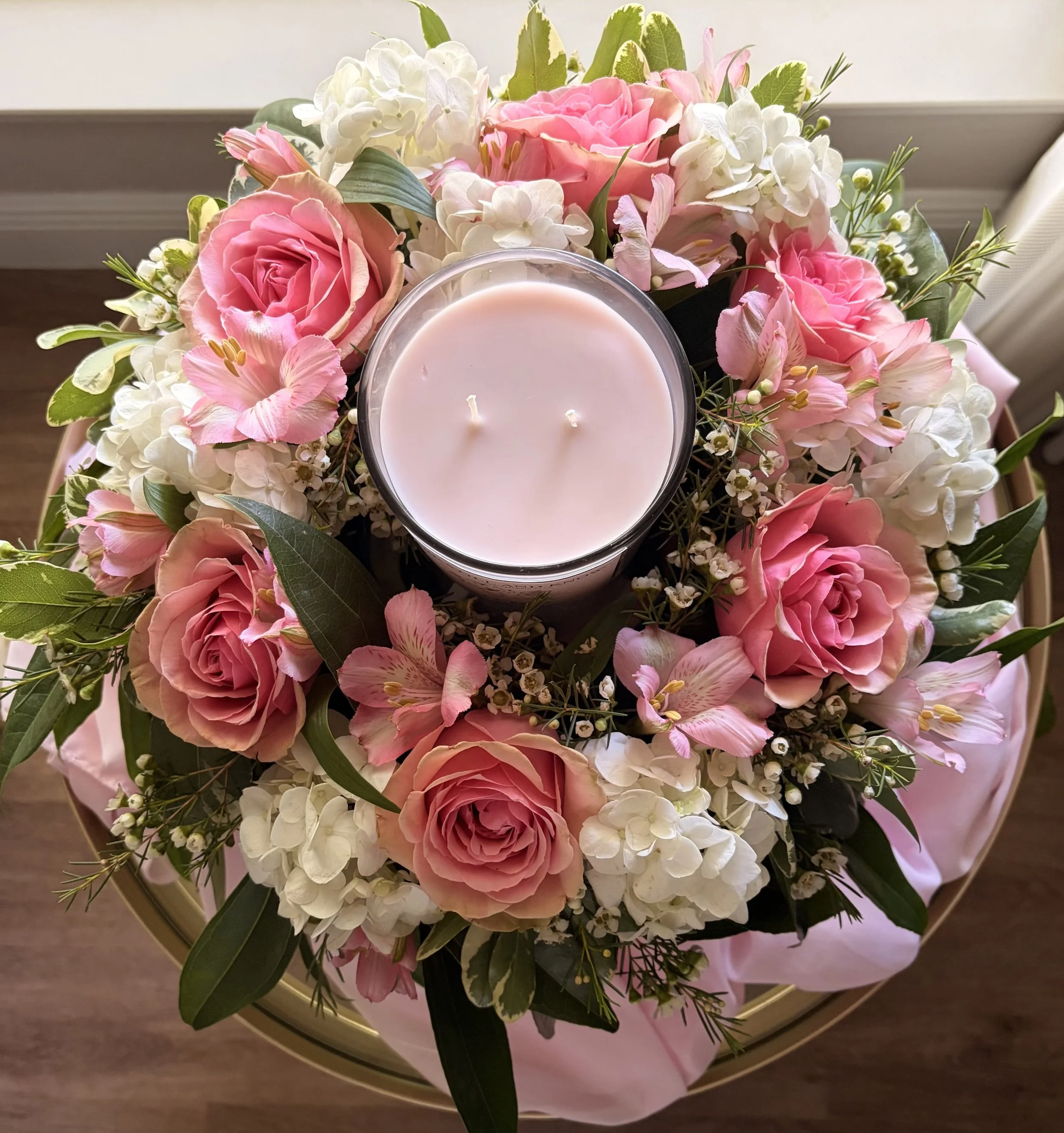 Pink roses and white hydrangeas arranged in a ring around a candle