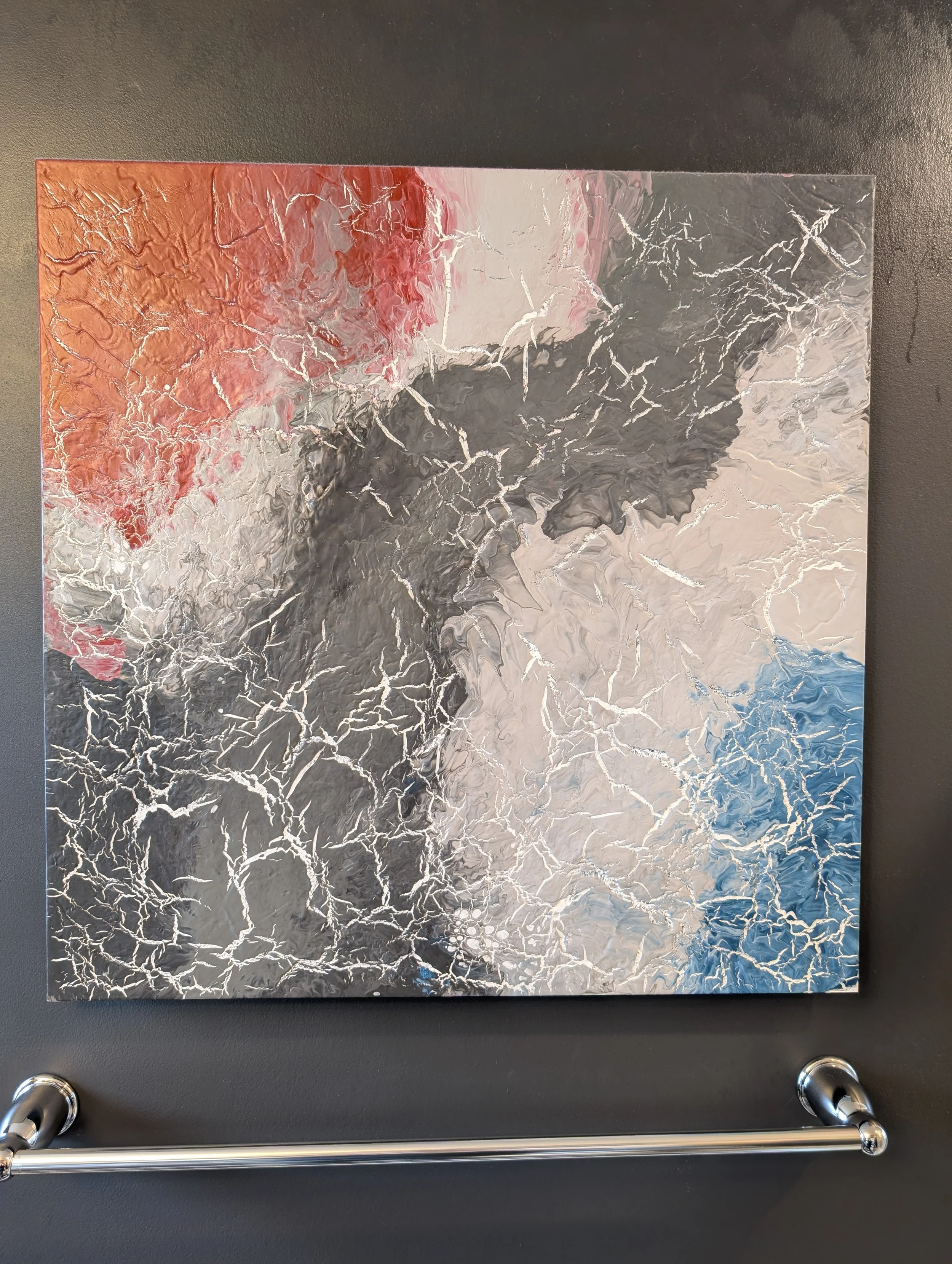 A paint poured painting in red, blue, and greys, with white cracks throughout.