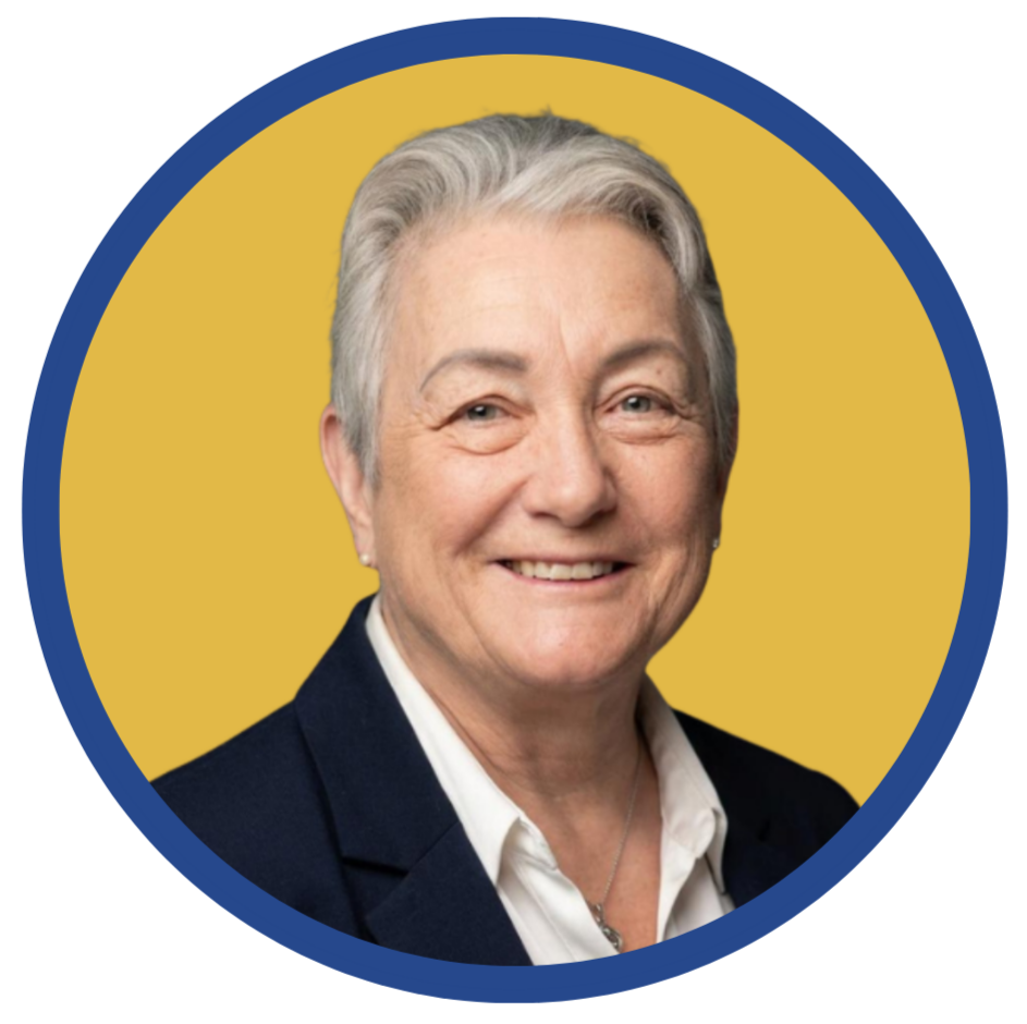 Portrait of an older woman with short gray hair, smiling, wearing a black blazer and white shirt, against a yellow background.