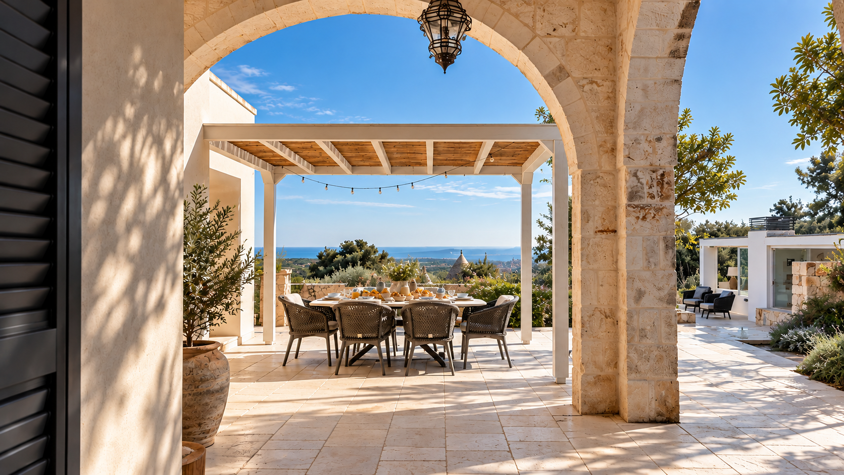 Outdoor patio with a dining table set and a view of the ocean in the distance.