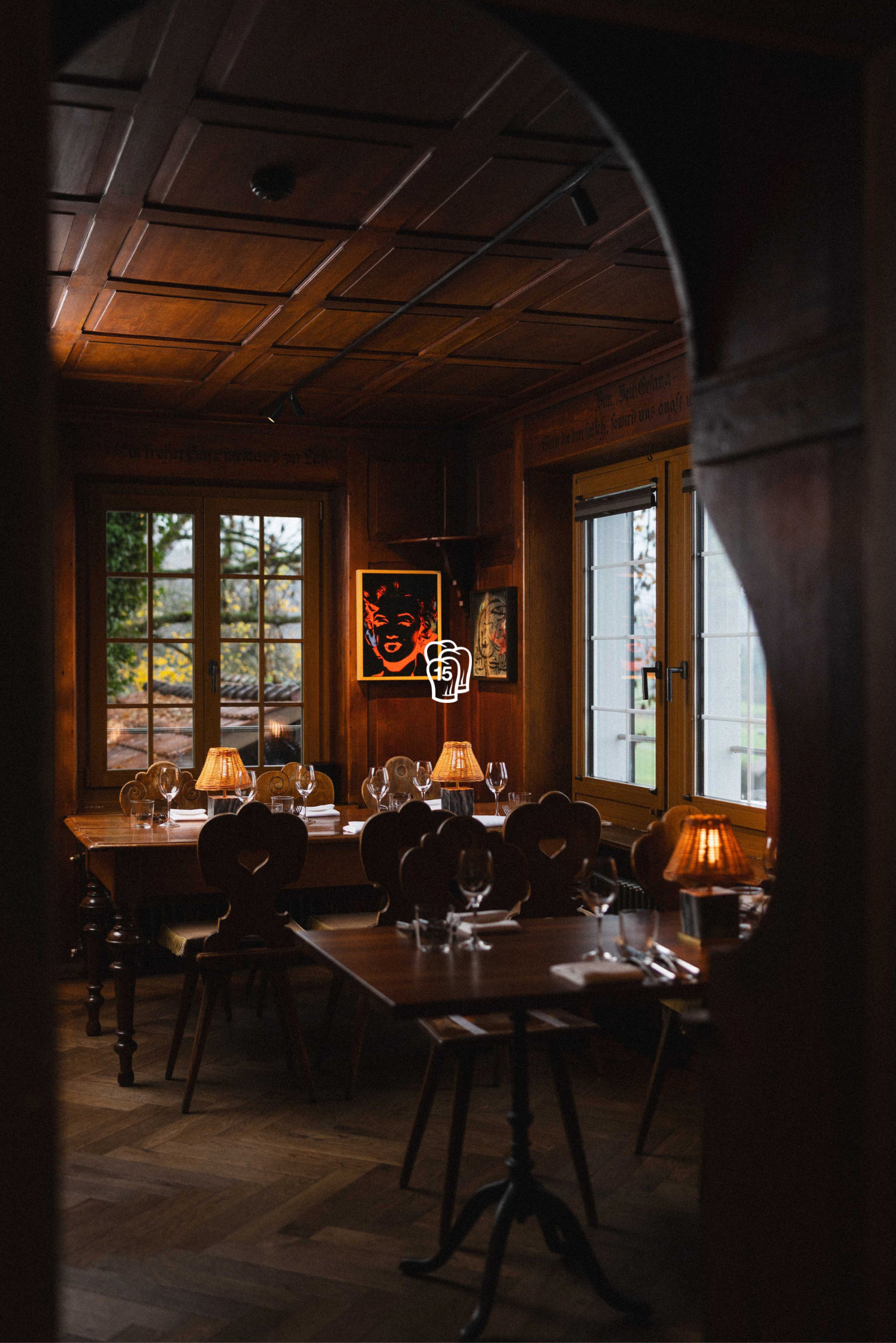 Rustikaler Essraum mit Holztisch, Kunst und Fenstern – Restaurant von Andreas Caminada