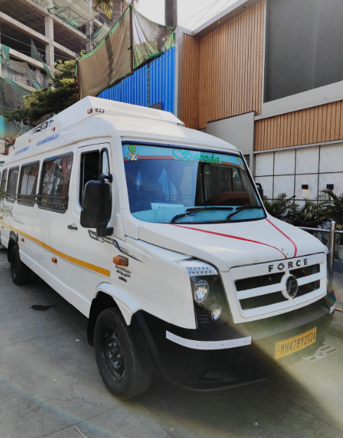White police or security van with a yellow stripe parked on a city street with modern buildings and construction in the background.