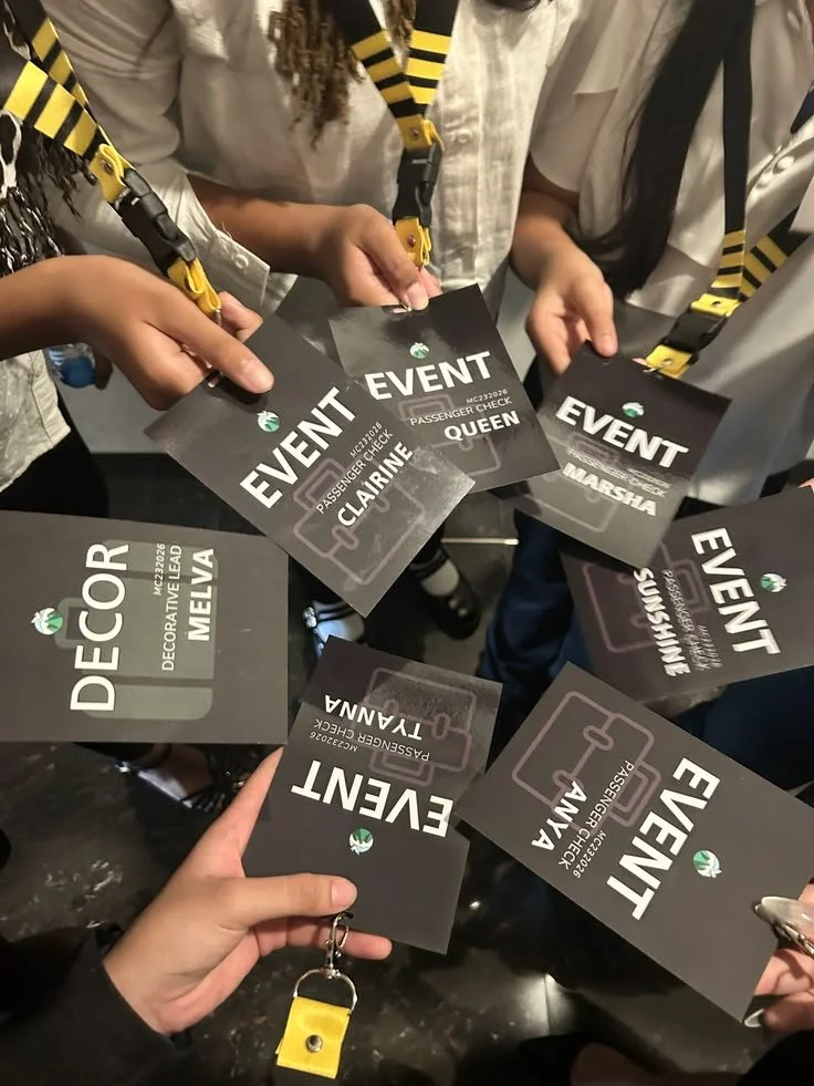 Group of people holding event passes with yellow and black striped lanyards.