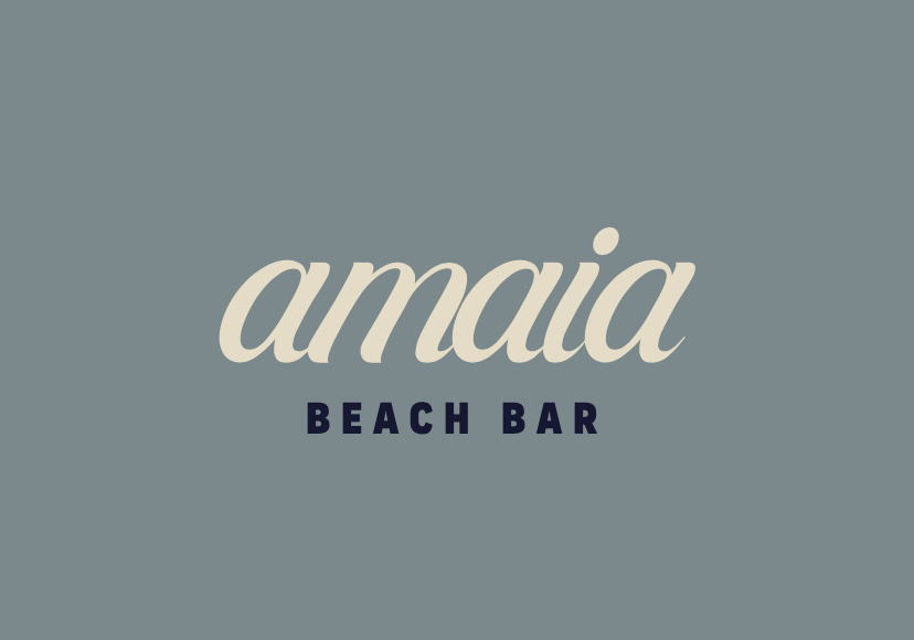 Logo for Amaia Beach Bar with the text 'amaia' in large cursive font and 'BEACH BAR' in smaller uppercase font on a blue background.