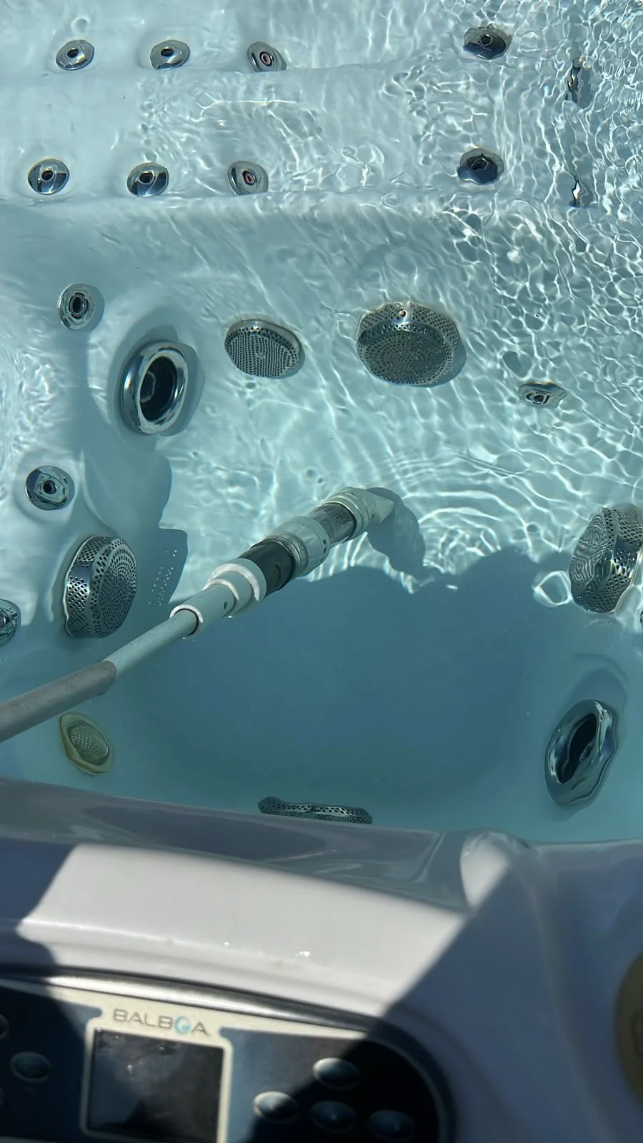View of the inside of a hot tub showing various metal jets and a control panel.
