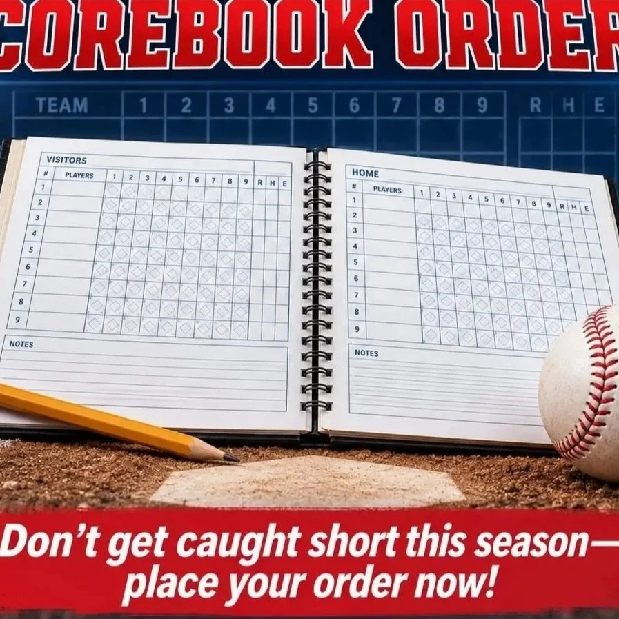 A baseball scorebook open on home plate with a baseball nearby. 