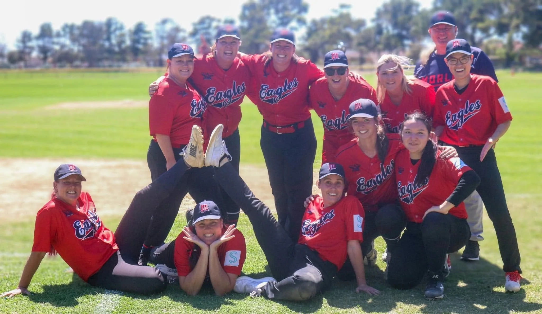 Group of women wearing red morley game shirts standing together on a baseball field