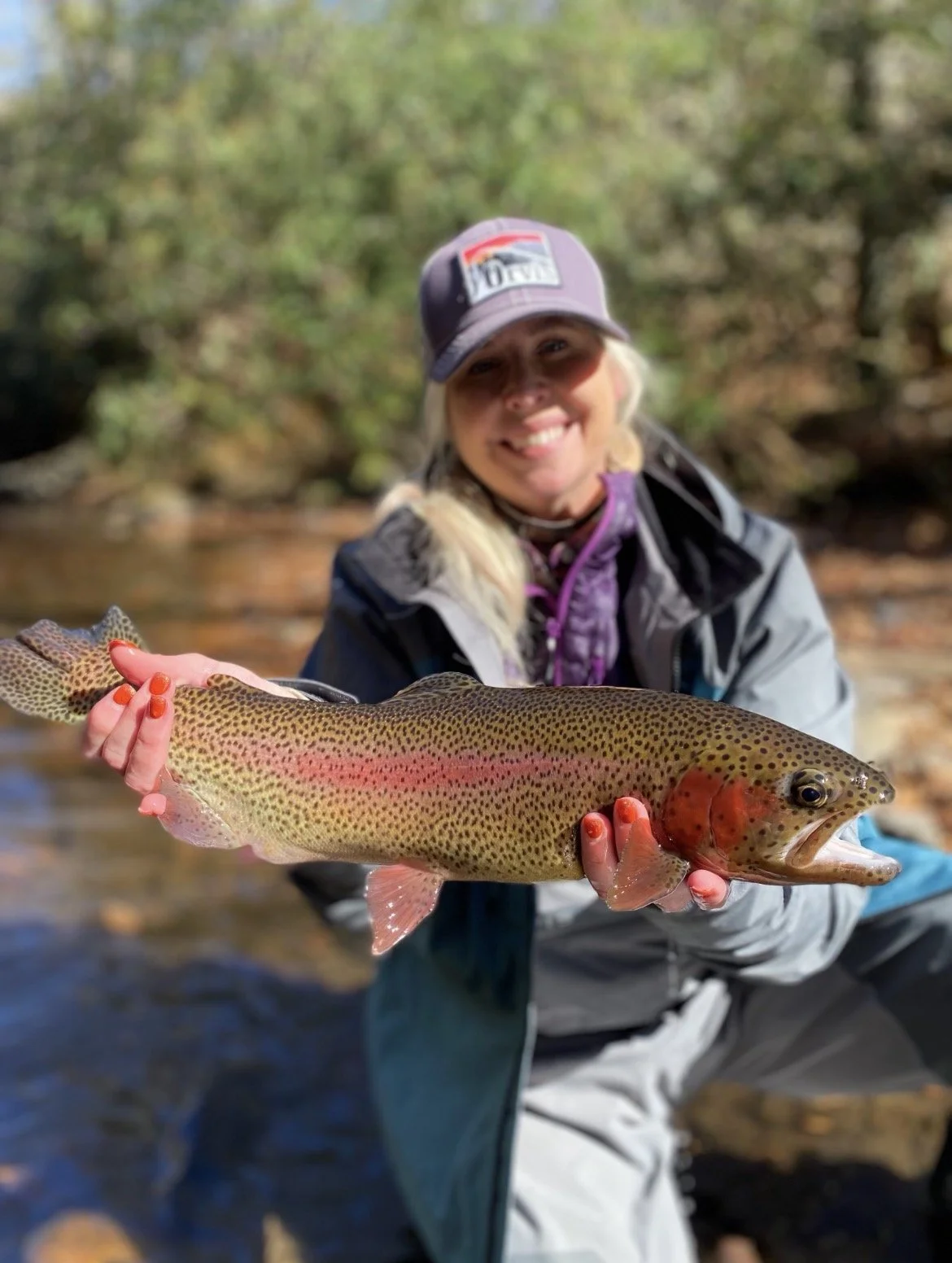 Angler holding a rainbow trout caught fly fishing near the Nantahala River.