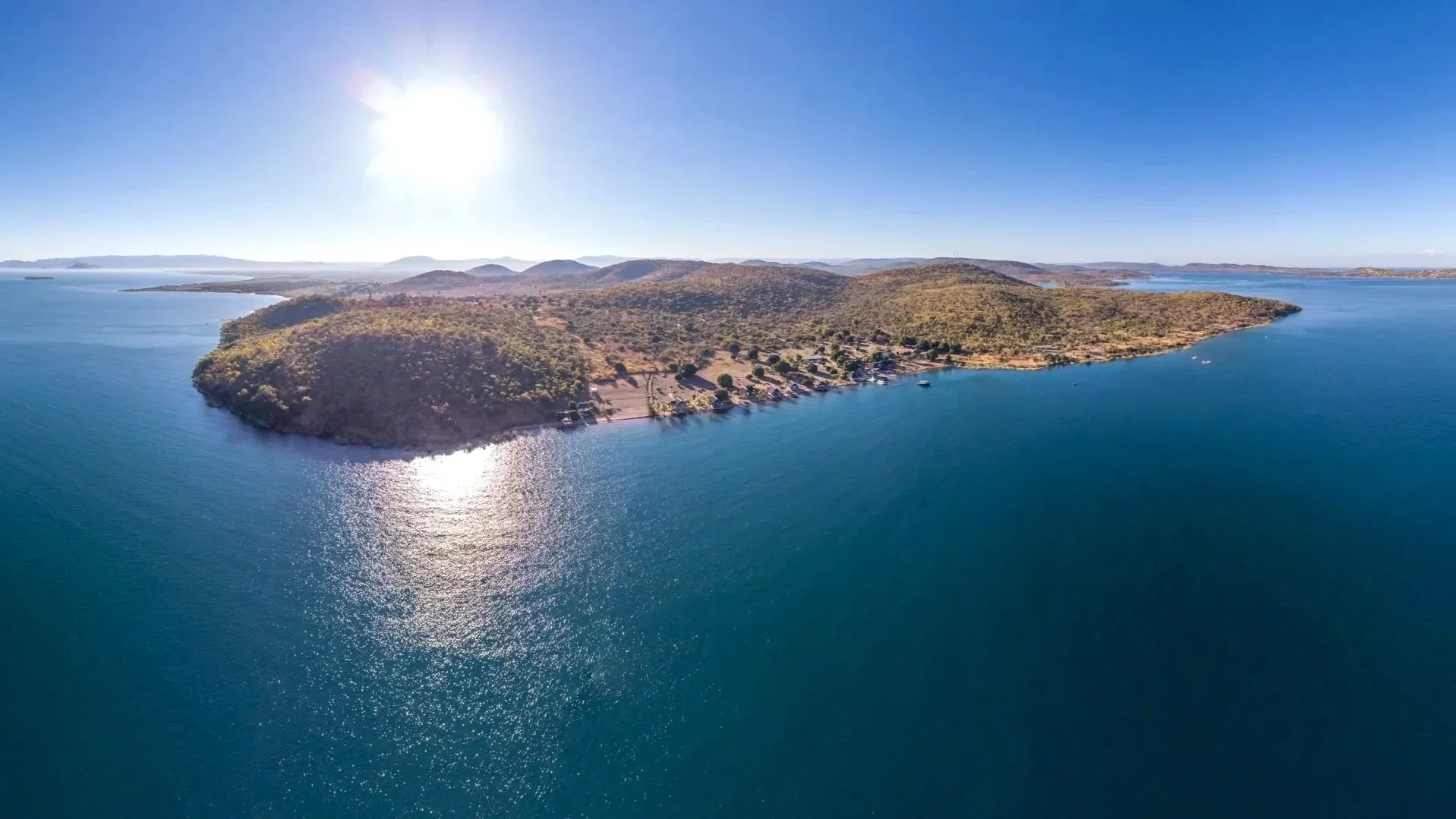 Aerial view of Lake Shore Lodge on the remote shores of Lake Tanganyika near Kipili, Tanzania, surrounded by clear blue water, wooded hills and islands.