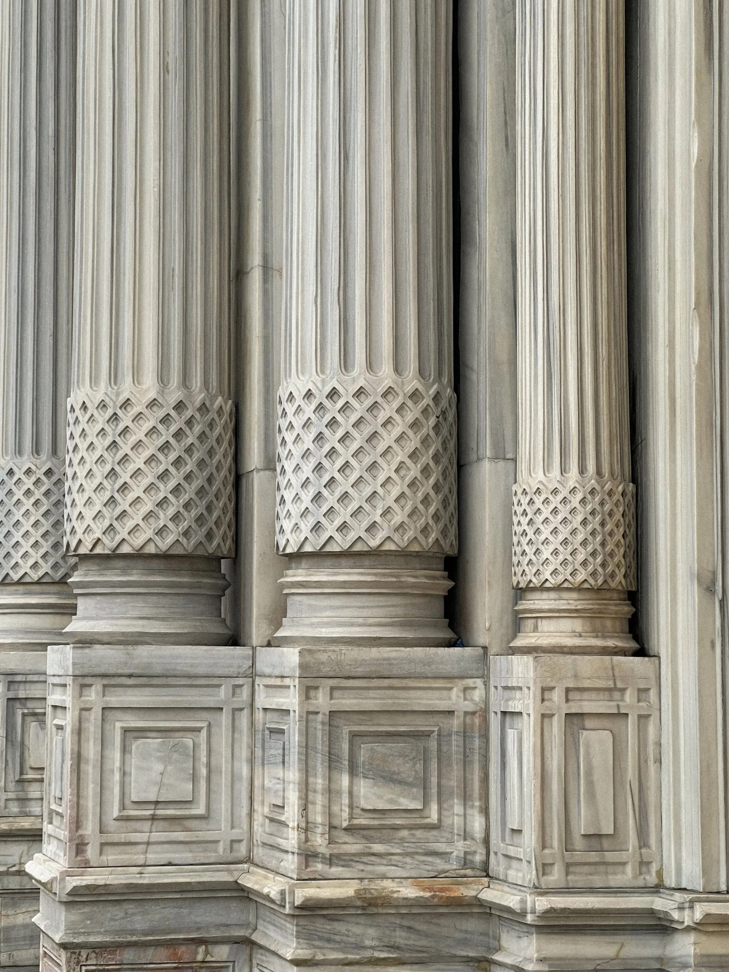 Close-up of ornate marble columns with detailed carvings and patterns in a classical architectural style.