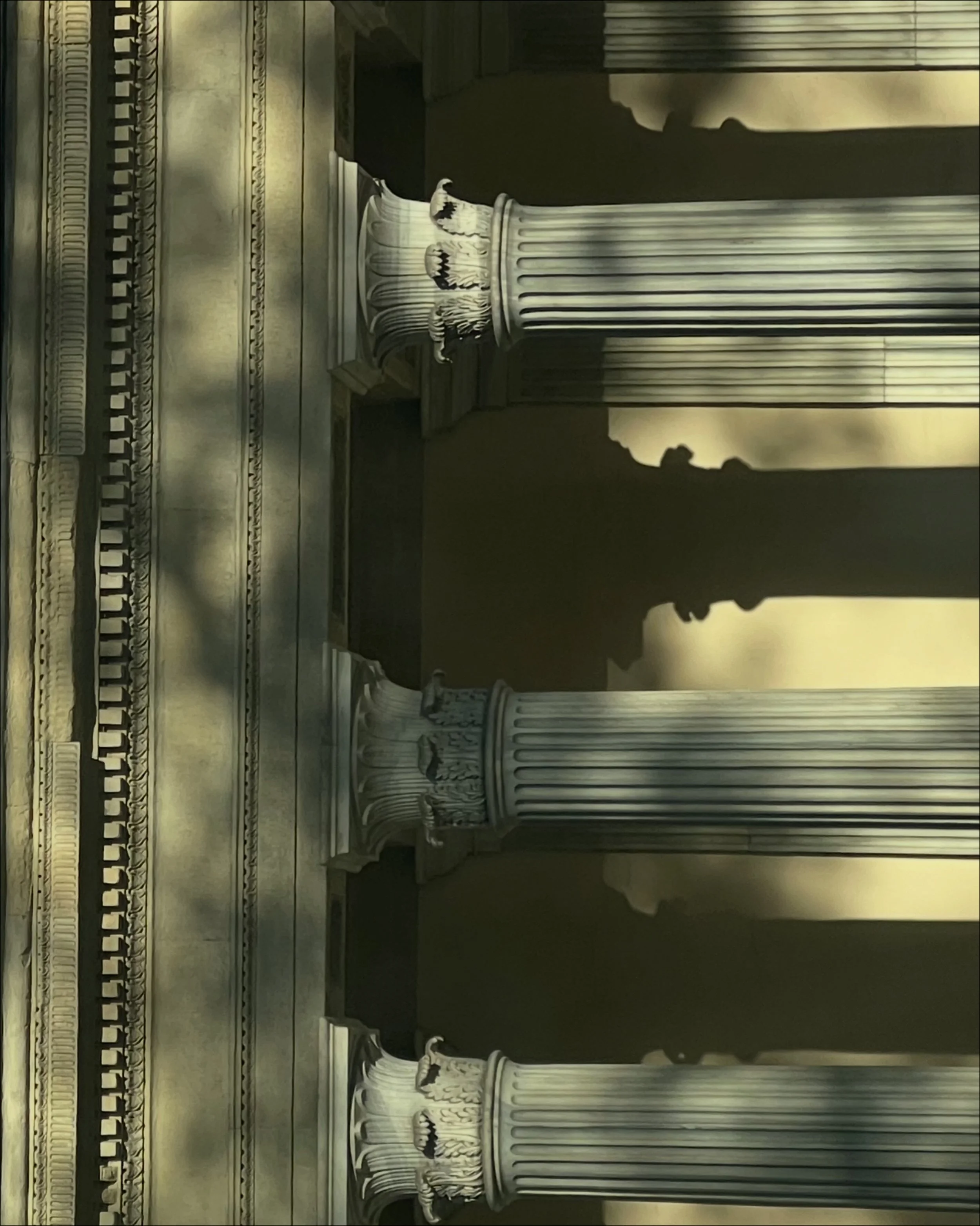 Interior view of a historic building featuring Greek-style columns with ornate capitals and intricate molding on the ceiling and walls.