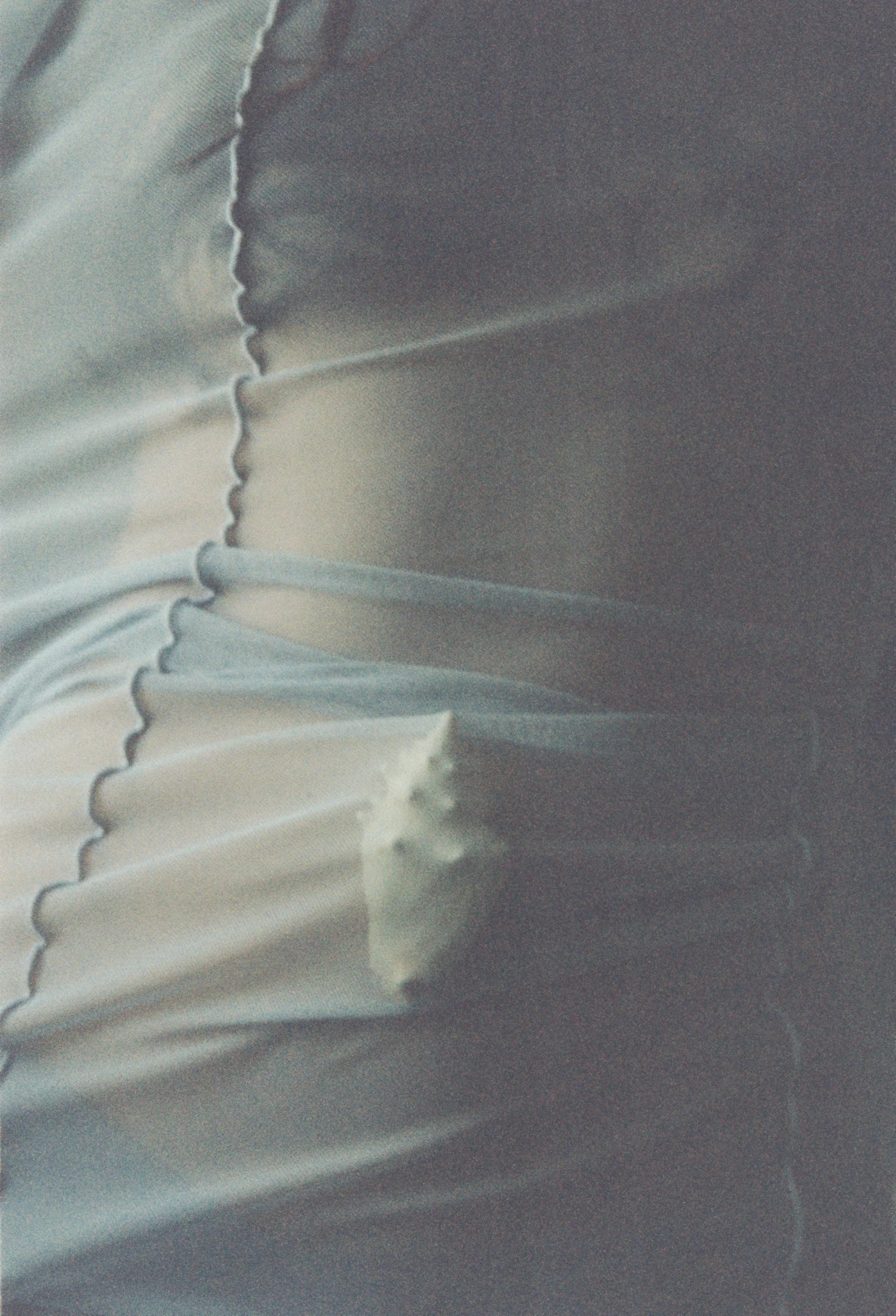 Close-up of silver or gray pleated fabric, possibly part of clothing.