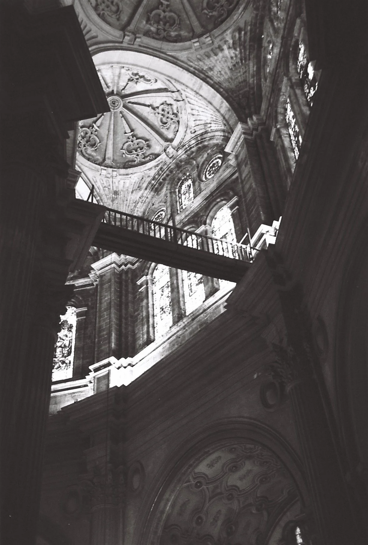 Interior view of a historic or religious building with ornate architectural details, stained glass windows, and a domed ceiling with decorative patterns.