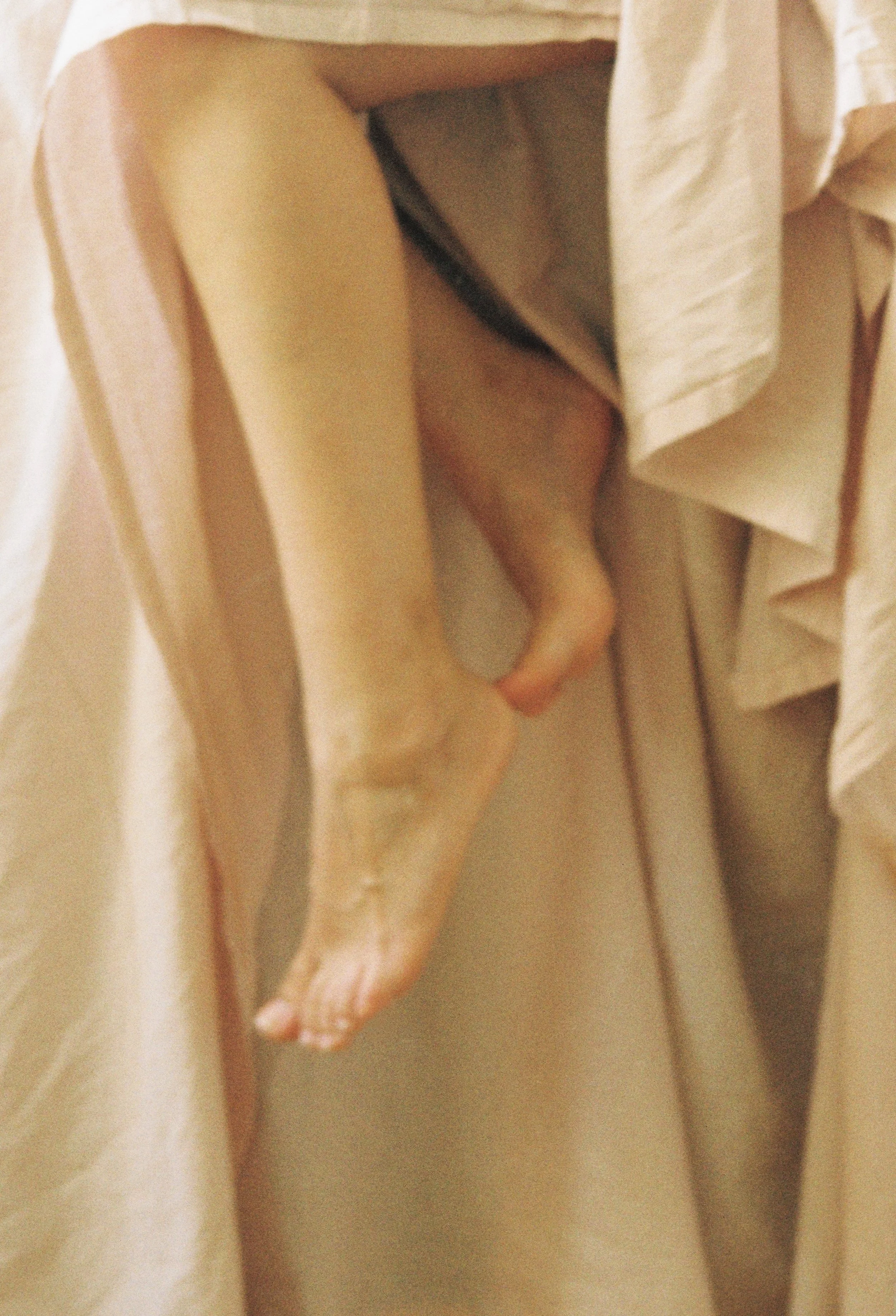 Close-up of a person's hand holding onto a beige curtain with pinked edges.
