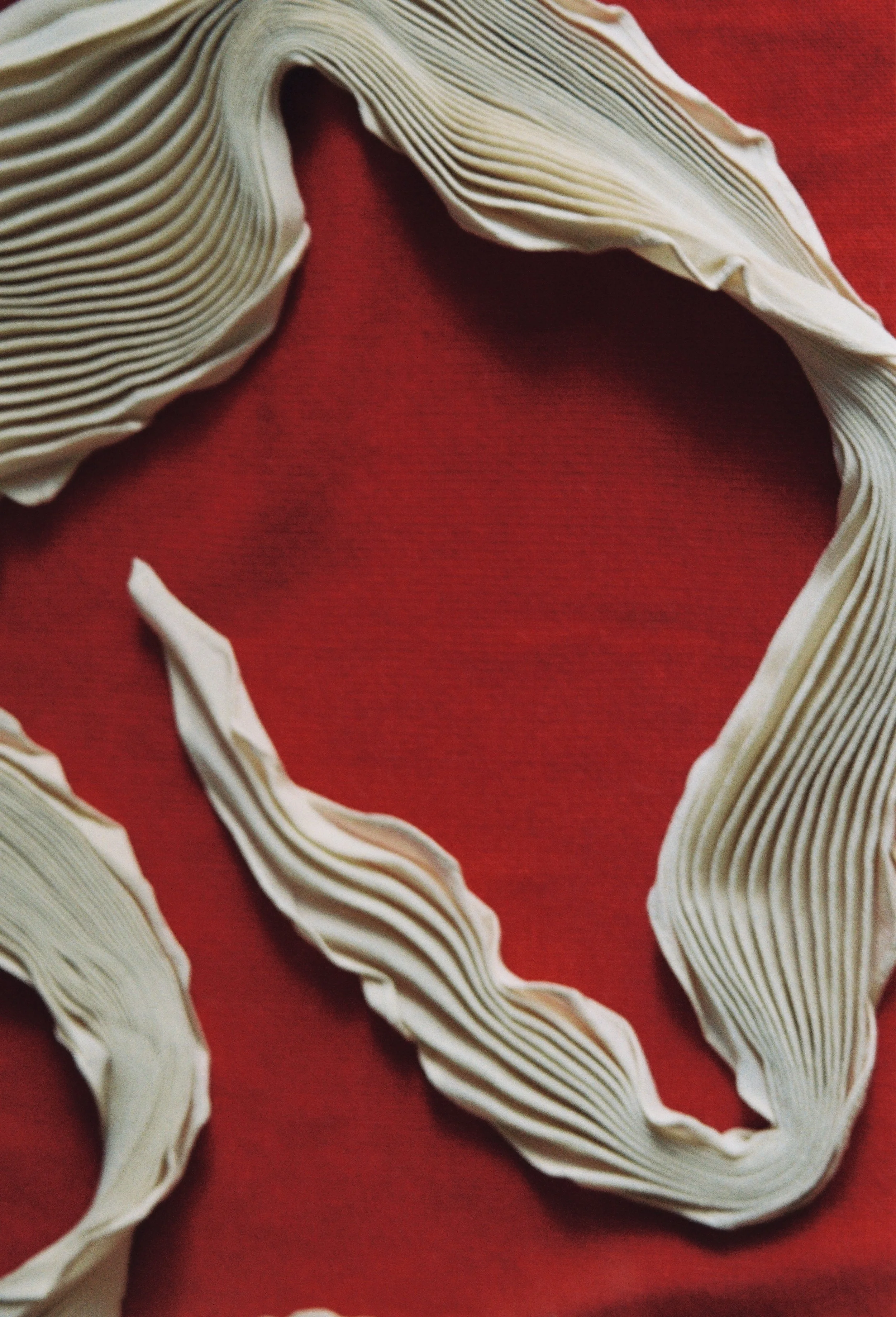 Detail of a cream pleated scarf and its folds.