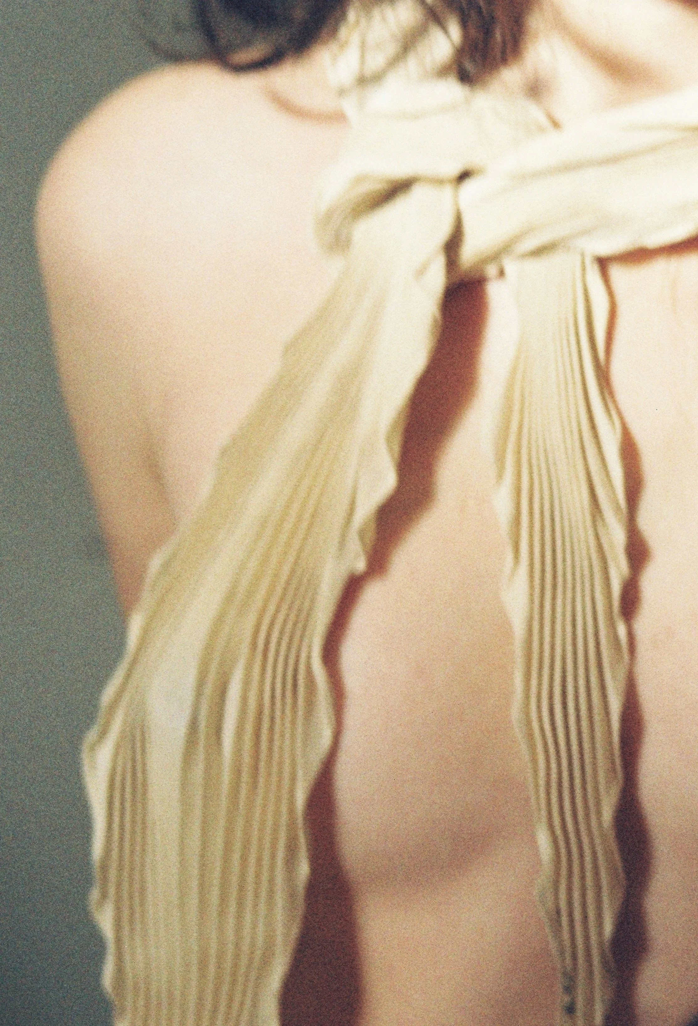 Close-up shot of a person's shoulder and part of scarf. The image is blurry and the person's face is not visible.