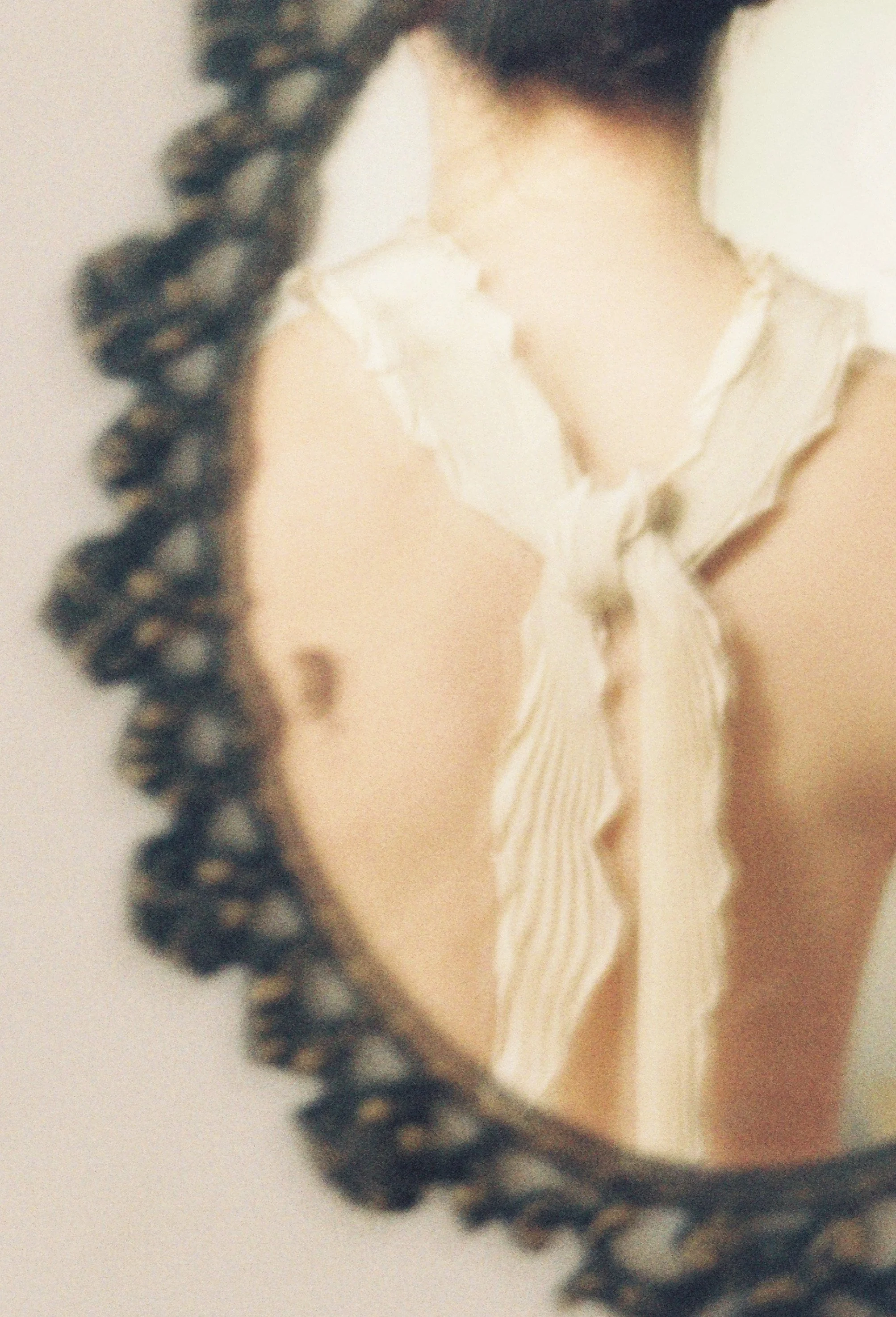 Close-up of a person's neck and shoulder, wearing a pleated scarf