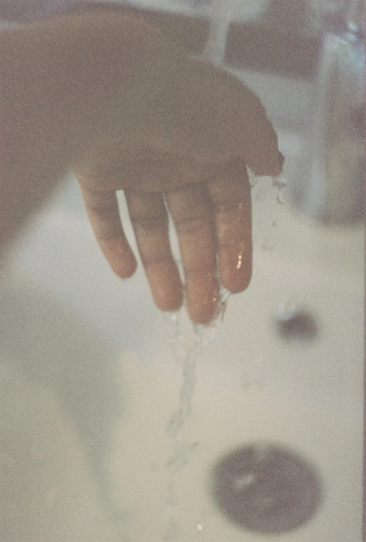 Close-up of a person's hand, with water droplets falling from their fingers.