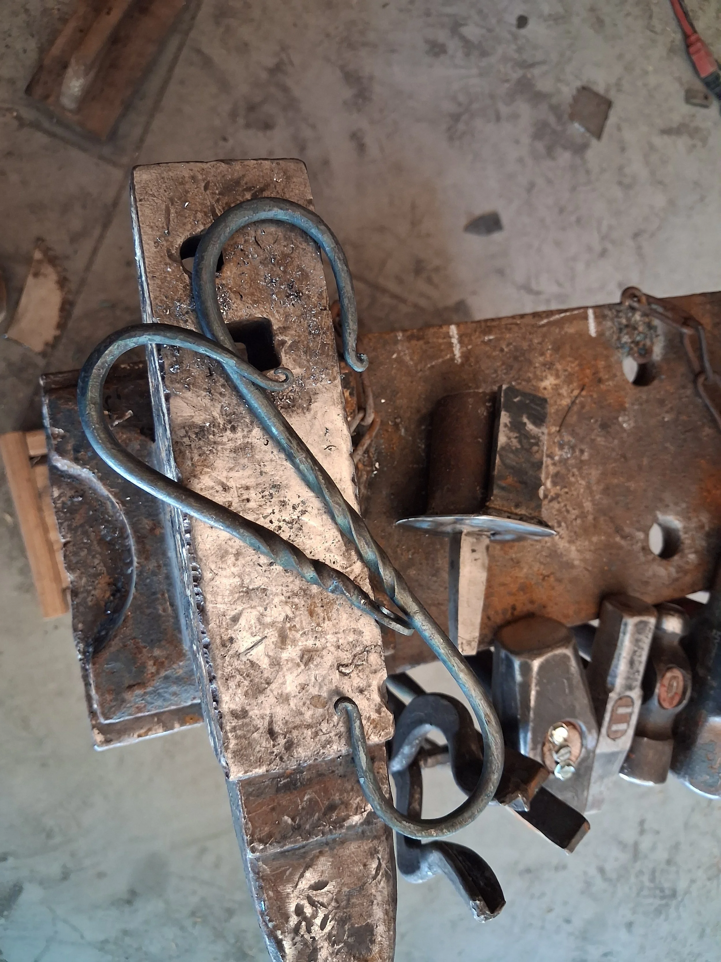 Metalwork on a workbench with metal hooks, tools, and scattered metal shavings.