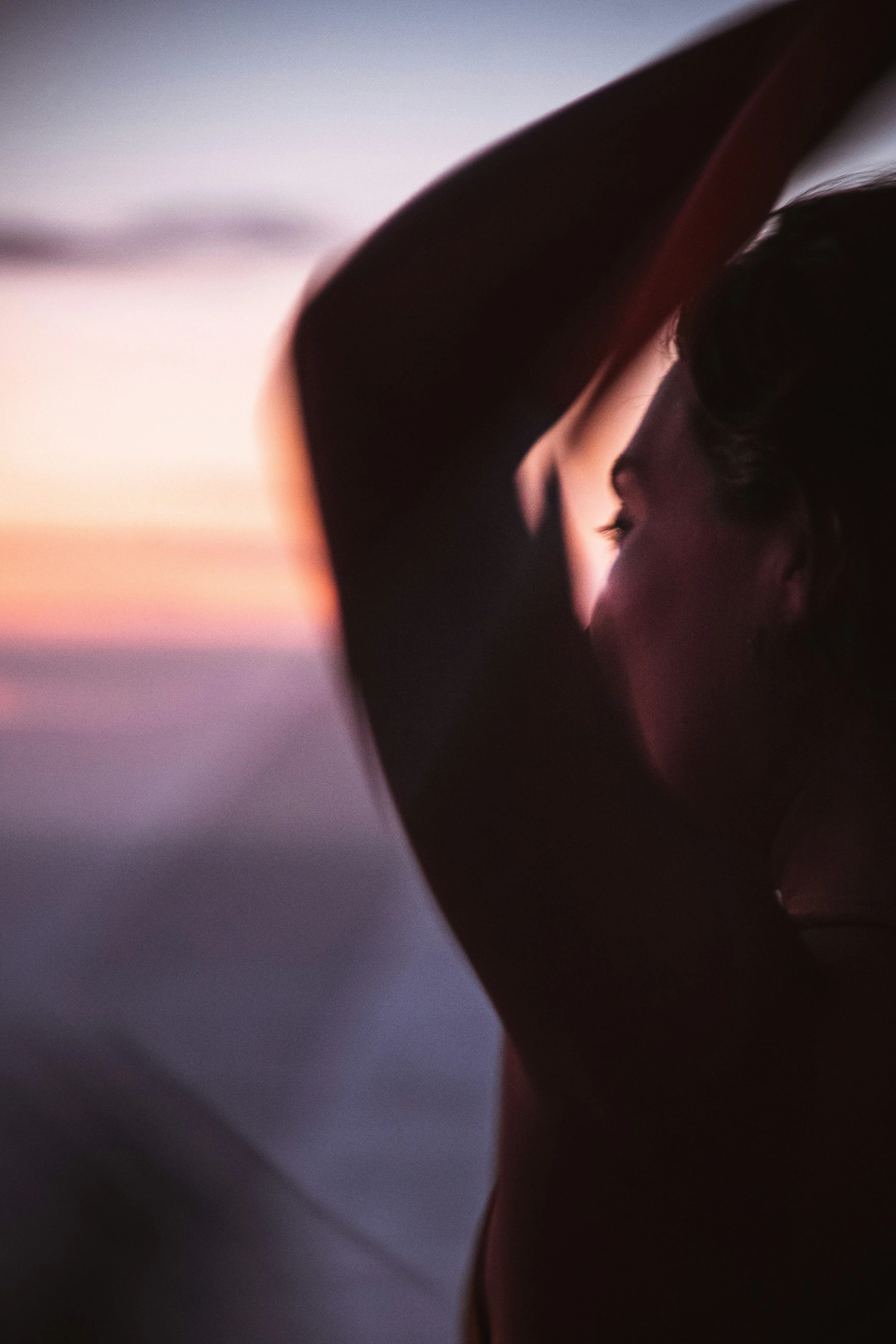 Mujer en movimiento frente al mar al atardecer.