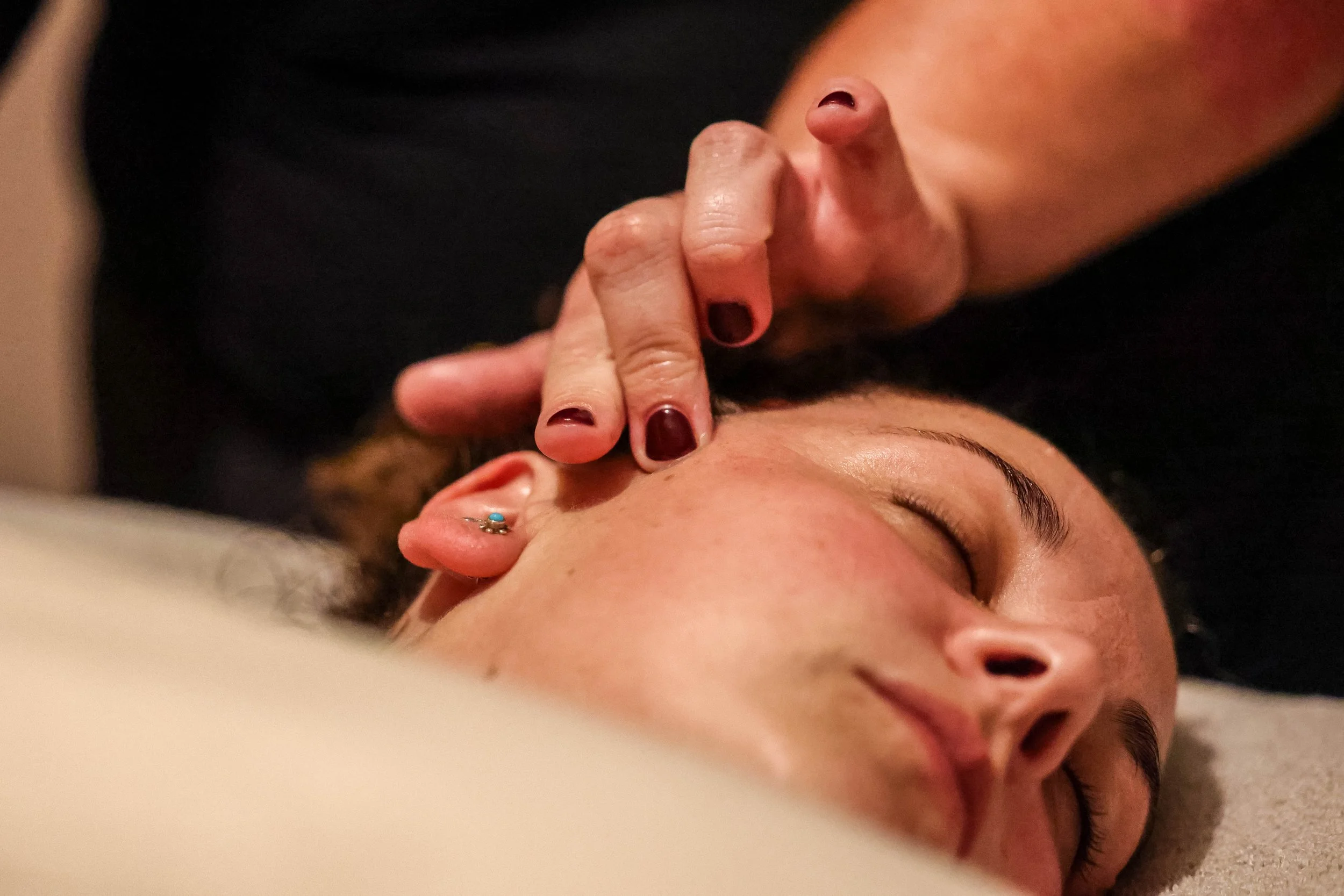 Close-up of a person receiving an eyebrow piercing while lying down