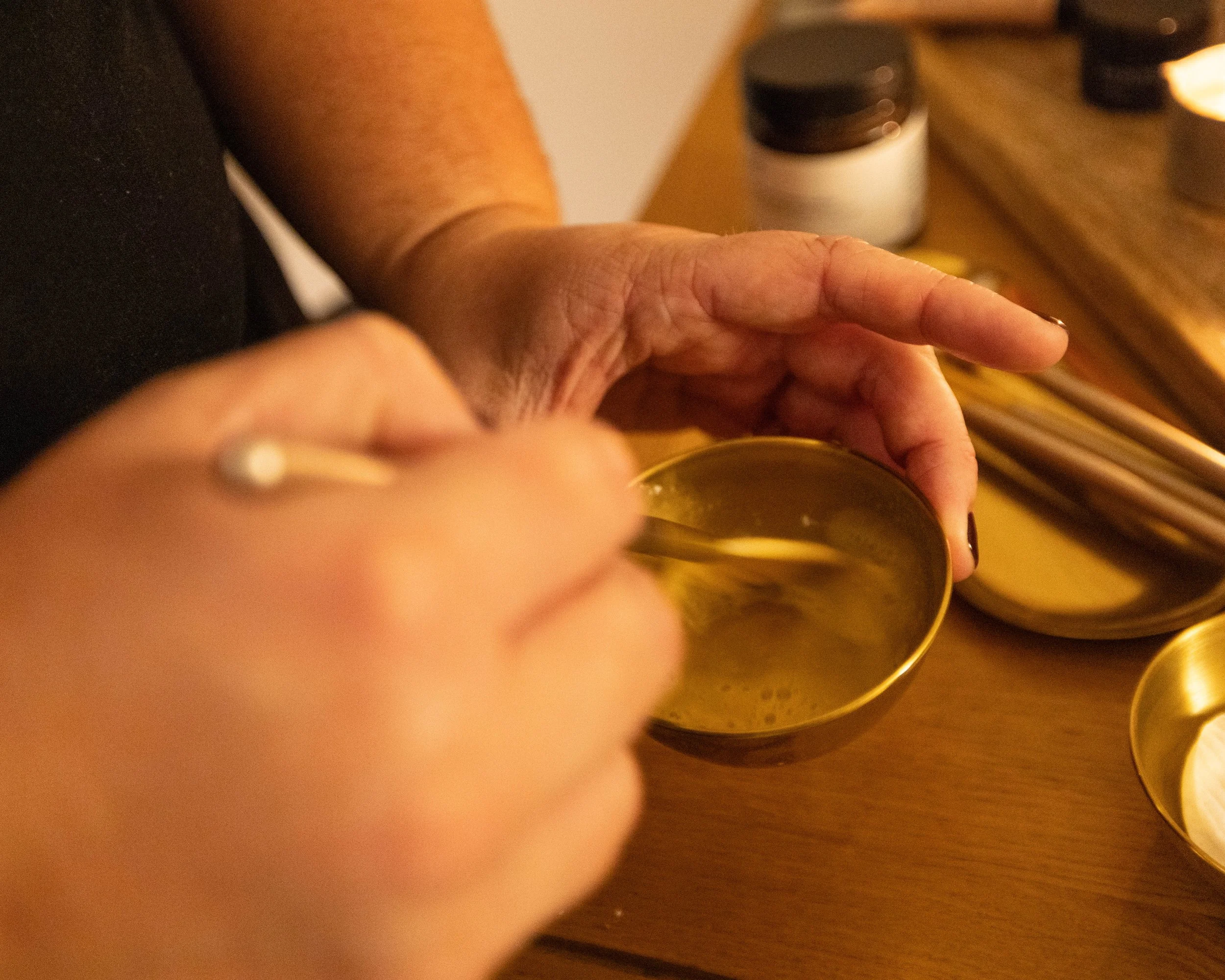Close-up of a hand reaching toward a glass of wine on a warmly lit restaurant table.
