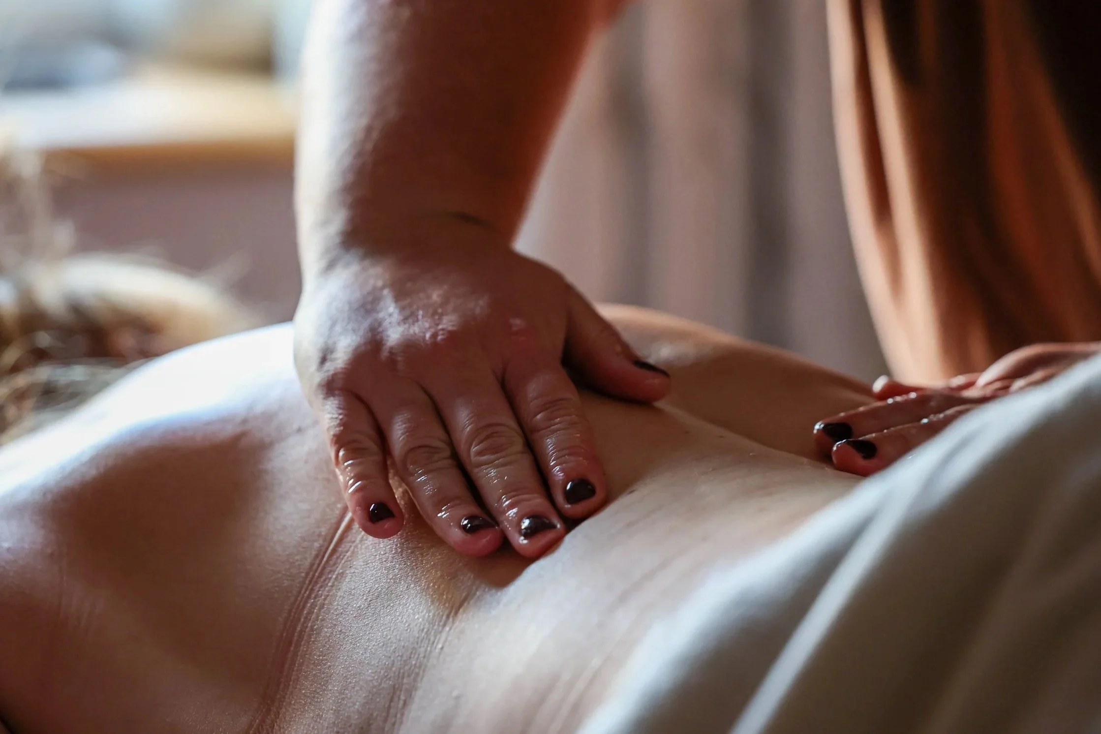 Close-up of a massage therapist’s hands applying pressure to a client’s back