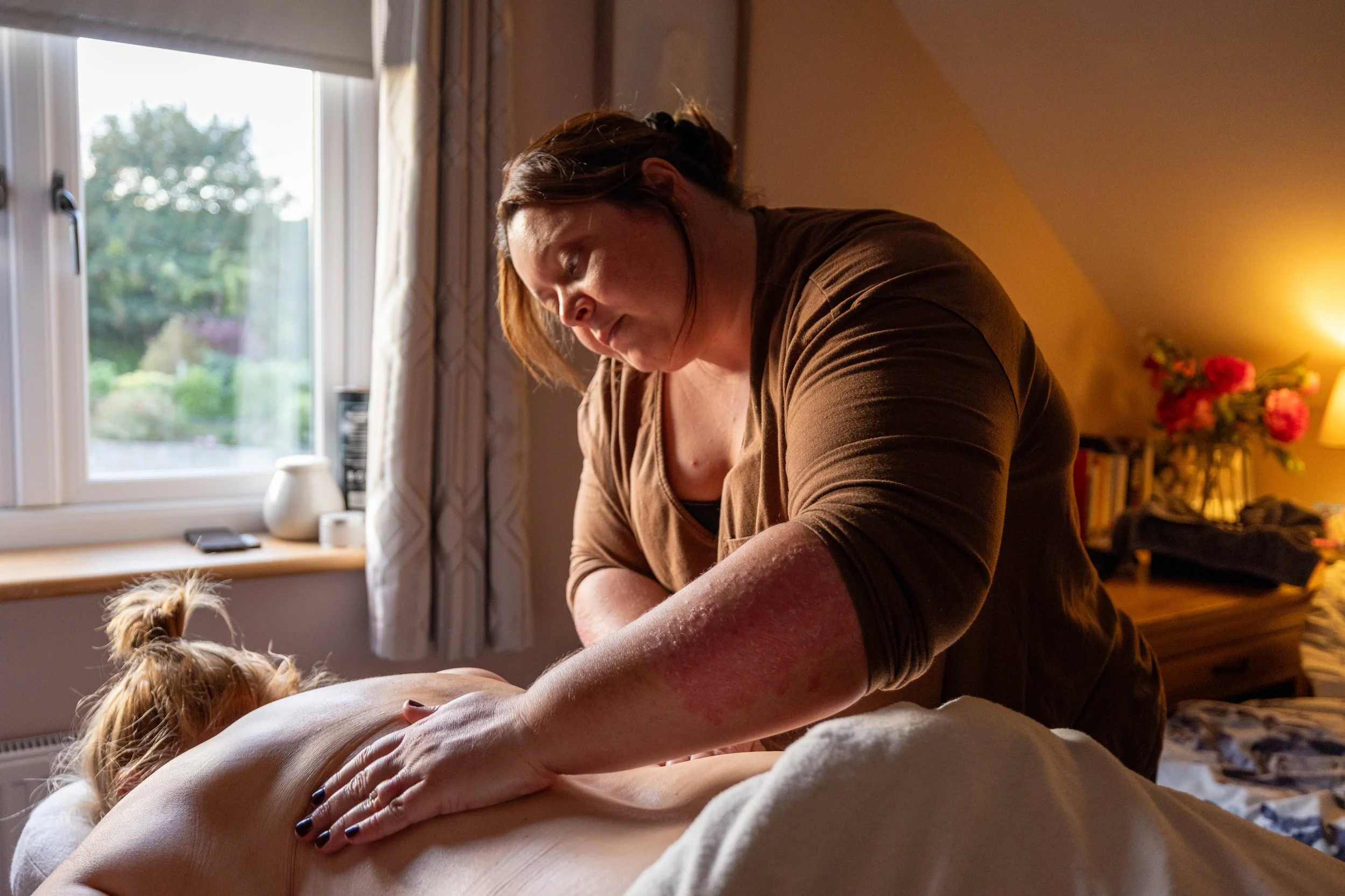 Woman massaging a person's leg at home, with a small dog nearby