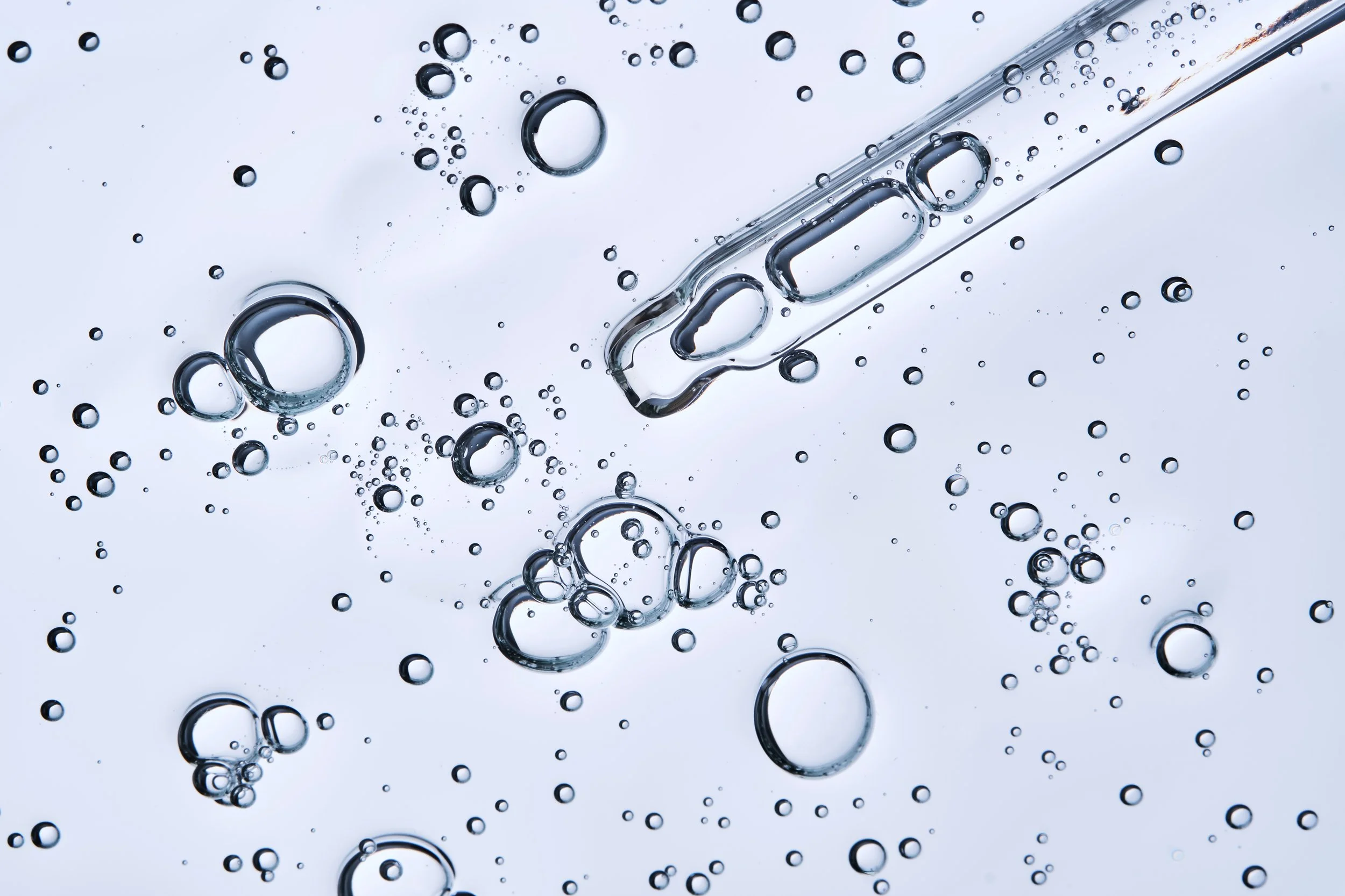 Close-up of air bubbles in clear liquid, possibly carbonated water, against a light background.