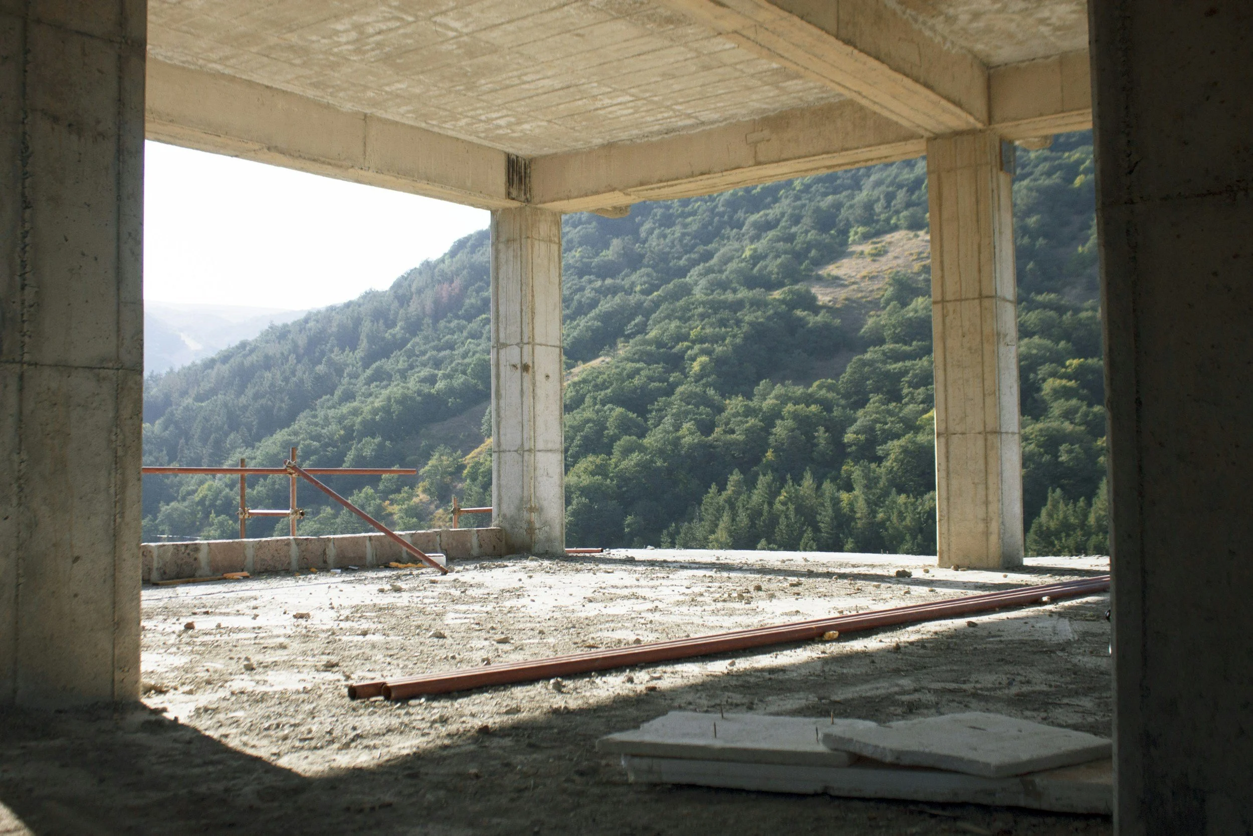 Under-construction building with concrete columns and an open view of green mountains in the background.