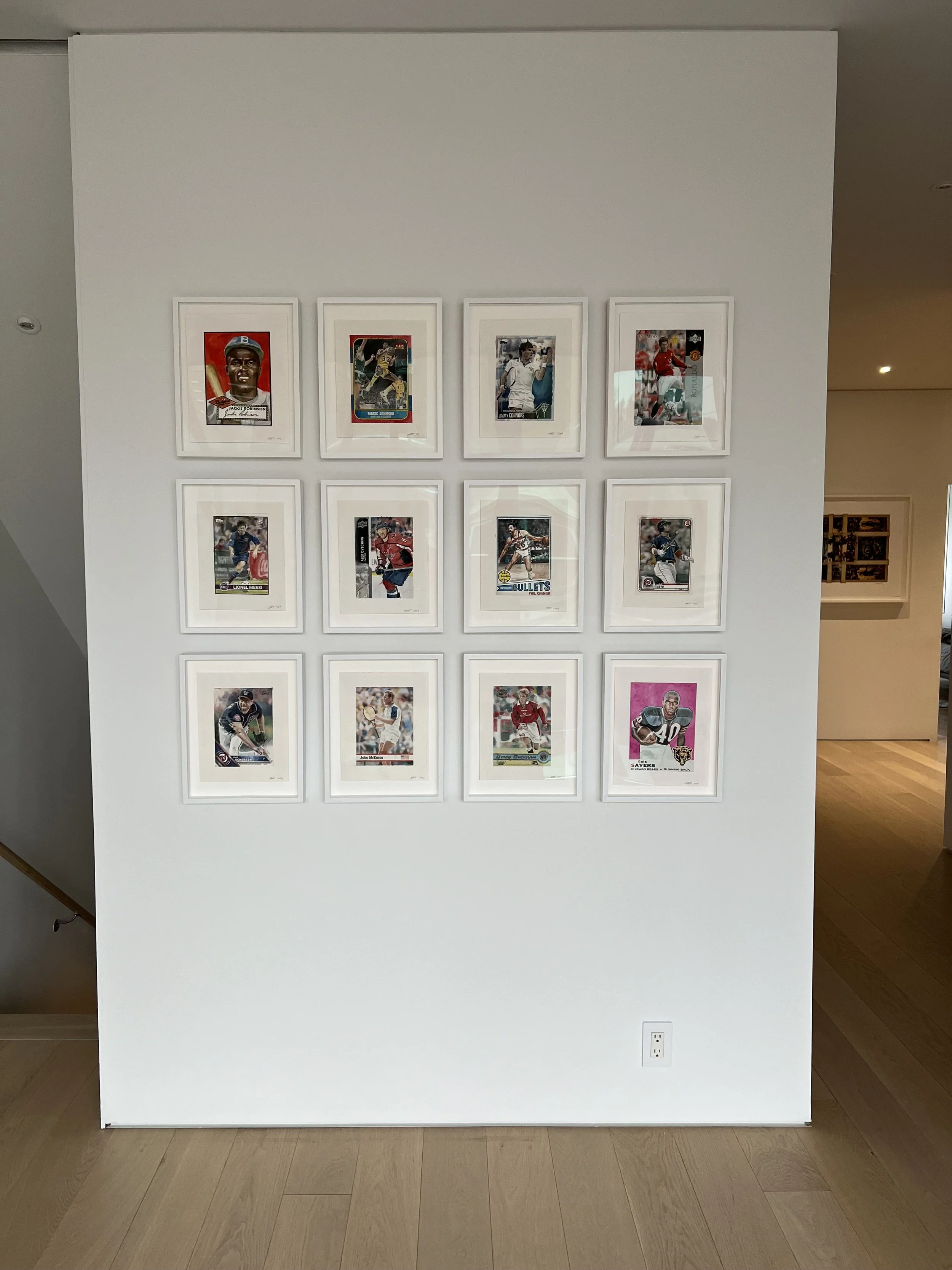 Display of sports trading cards framed and hung on a white wall in a gallery or museum setting.