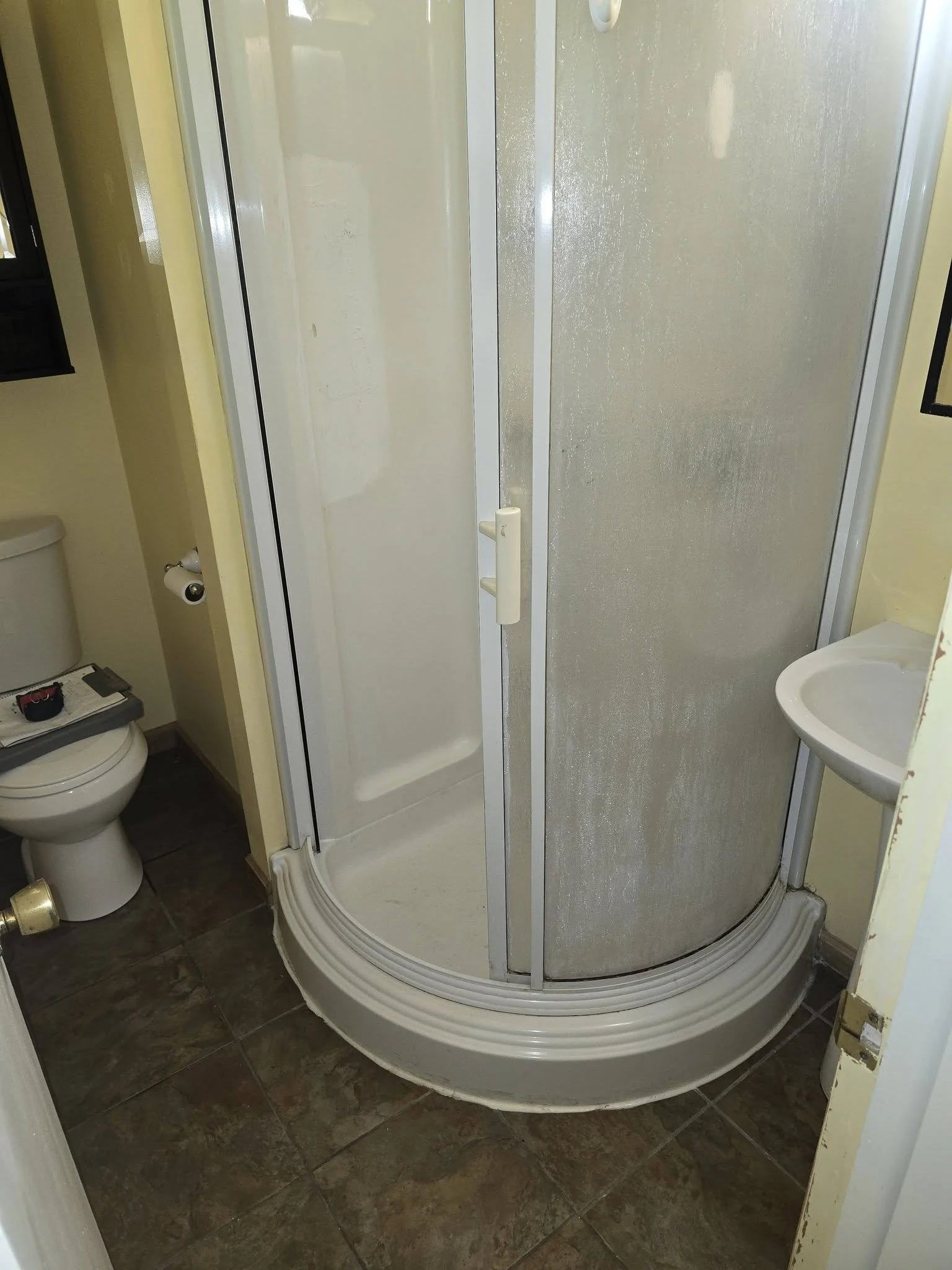 The old round corner shower stall with frosted sliding doors before removal