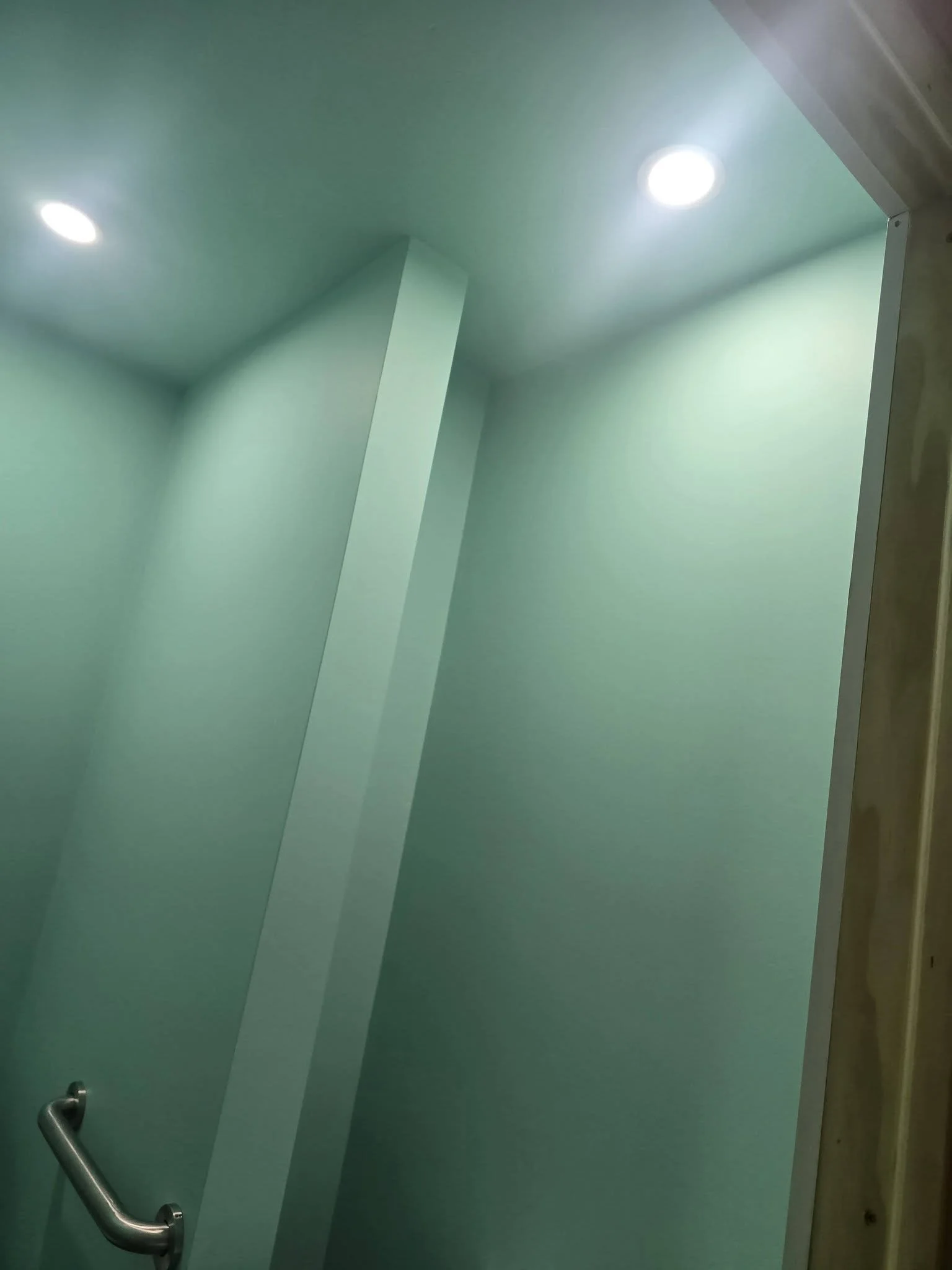 Recessed lighting and a grab bar inside the finished half bath