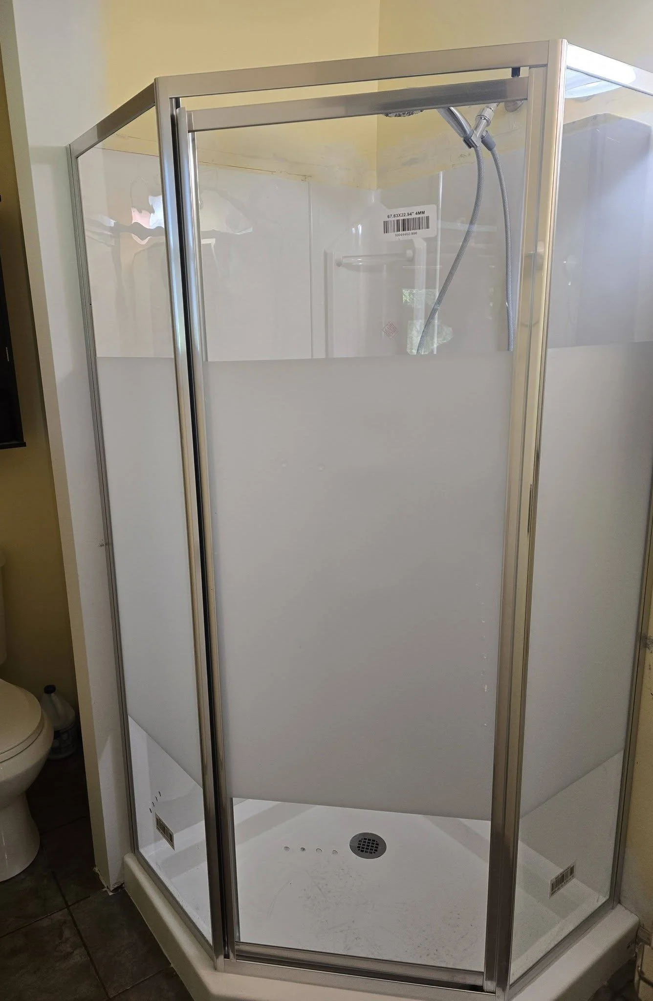 The new corner shower with framed glass enclosure and white base installed