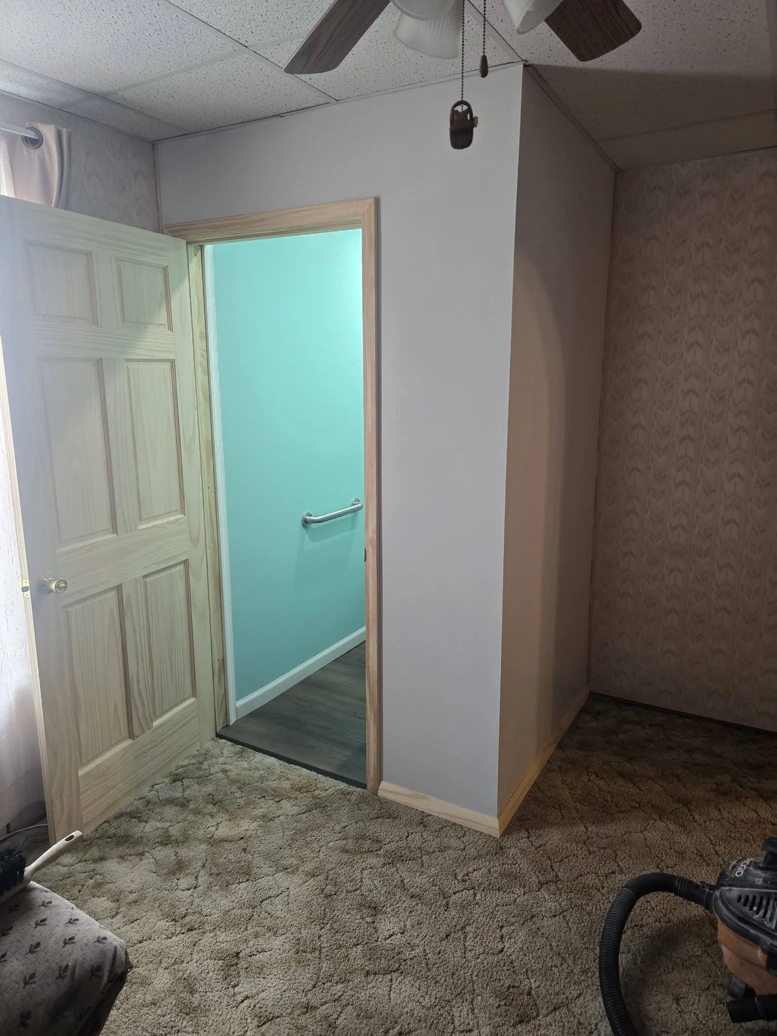 The finished enclosure with its new pine door open, showing the new half bath