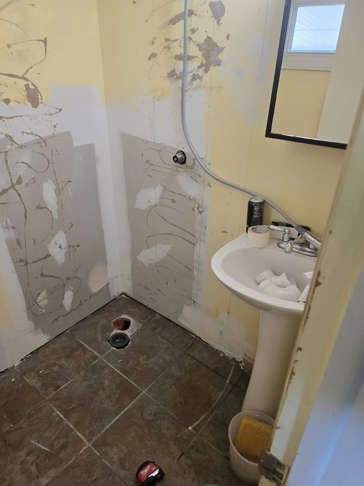 Shower drain rough-in in the floor with walls scraped and patched