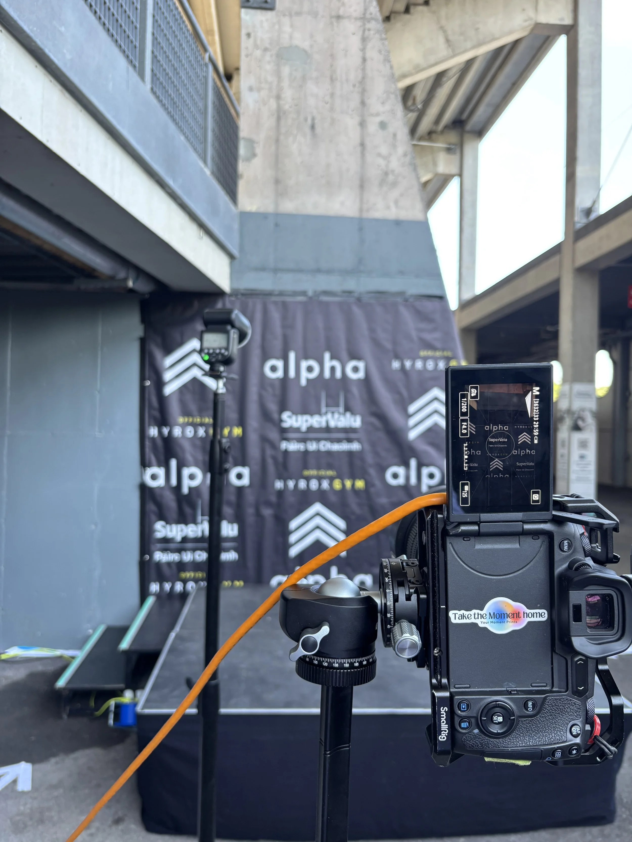Your Moment Prints camera set up facing the photo backdrop at a fitness event