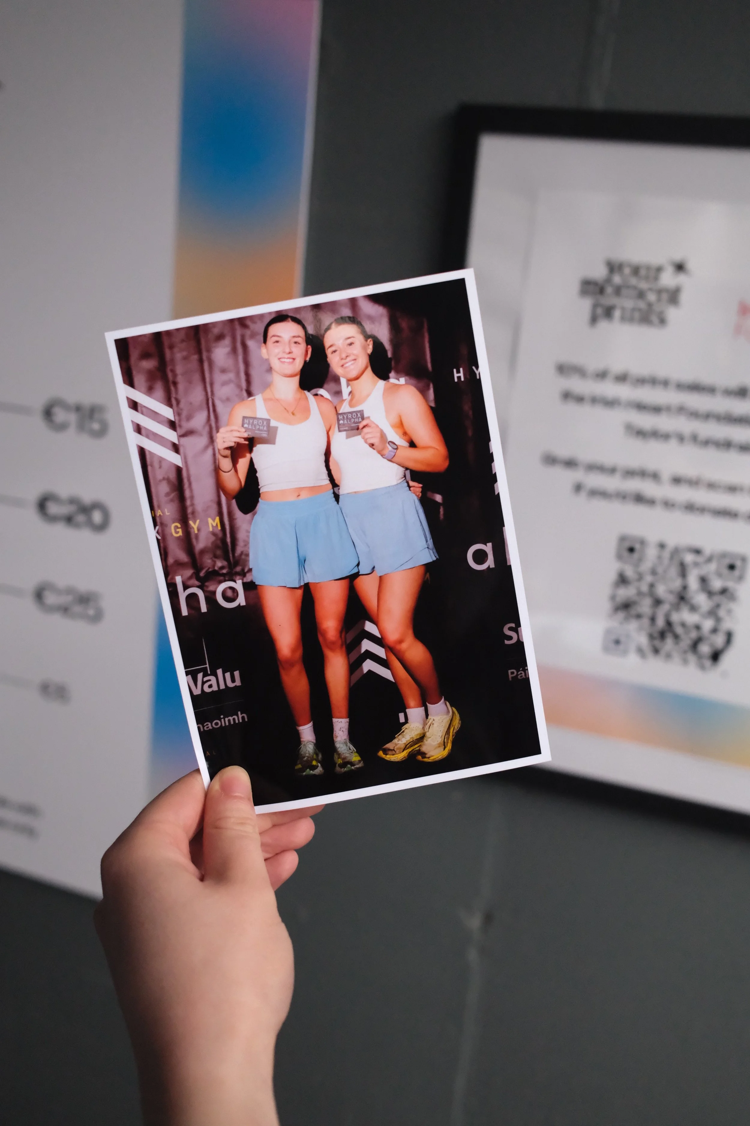 A hand holding a freshly printed Your Moment Prints photo of two finishers