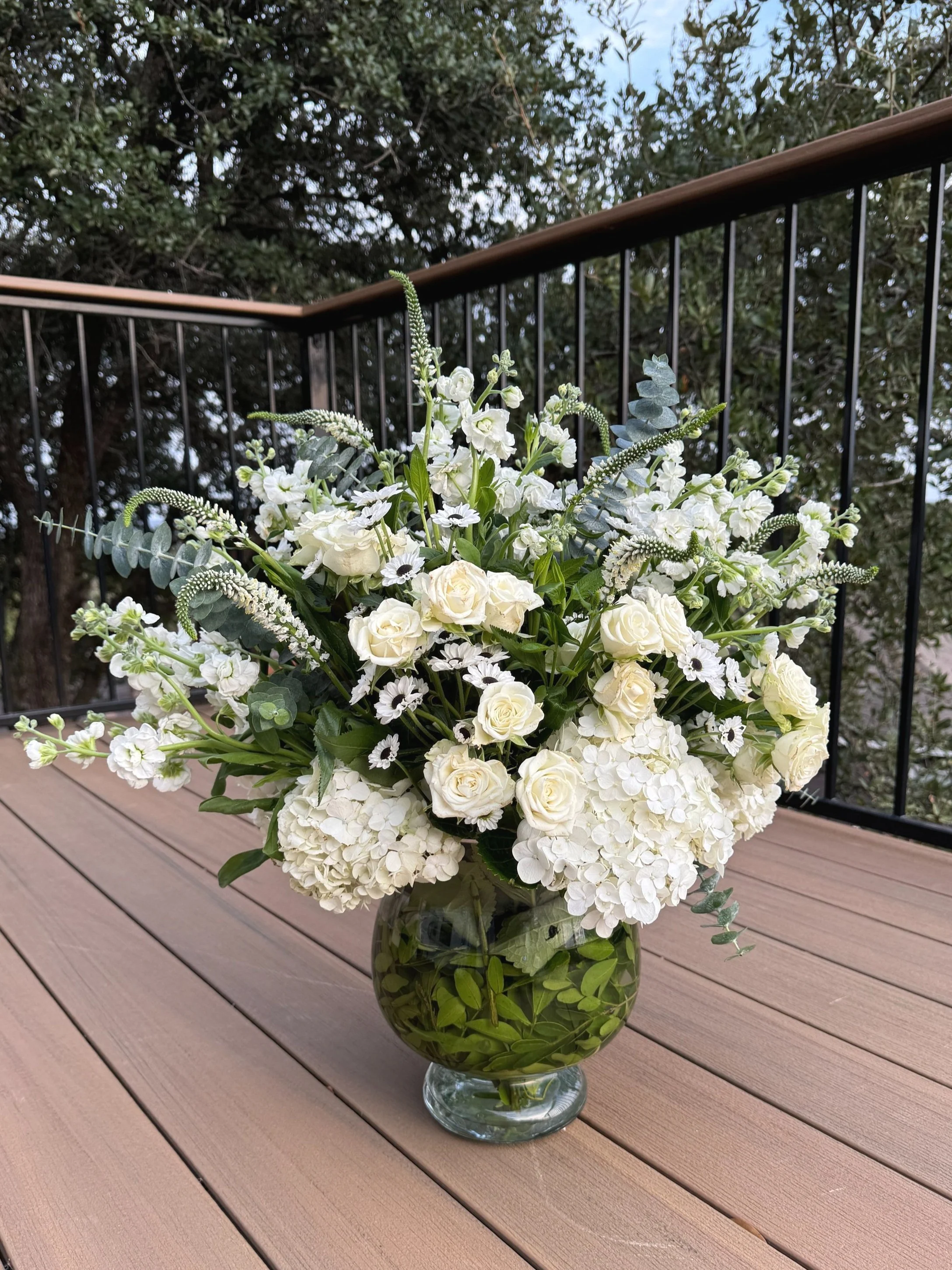 A large bouquet of white flowers in a clear glass vase